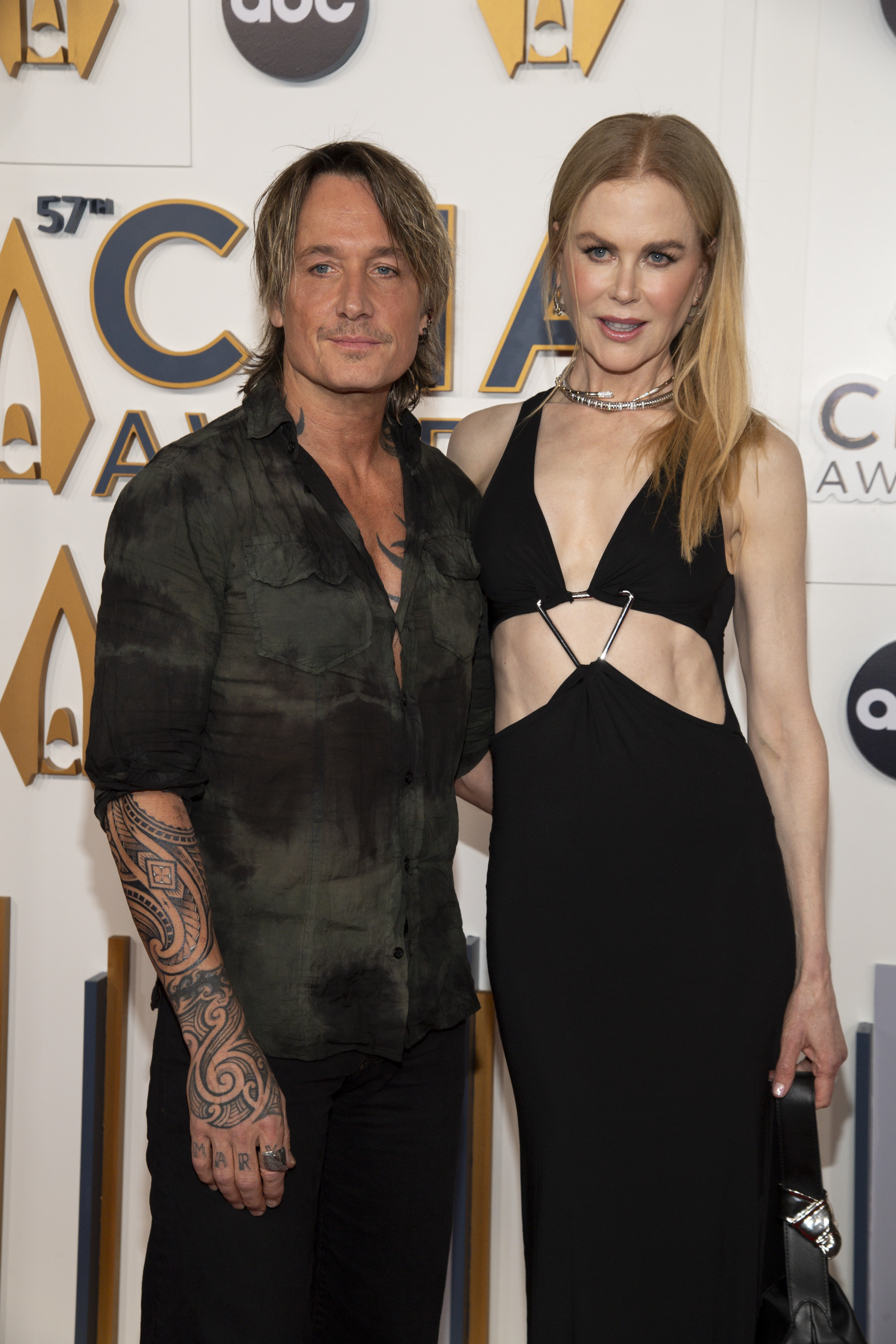 At the 57th Annual CMA Awards, Nicole Kidman appears alongside Keith Urban in a sleek black cut-out gown. Her hair is pin-straight and parted in the middle, framing a dramatic, edgy ensemble.