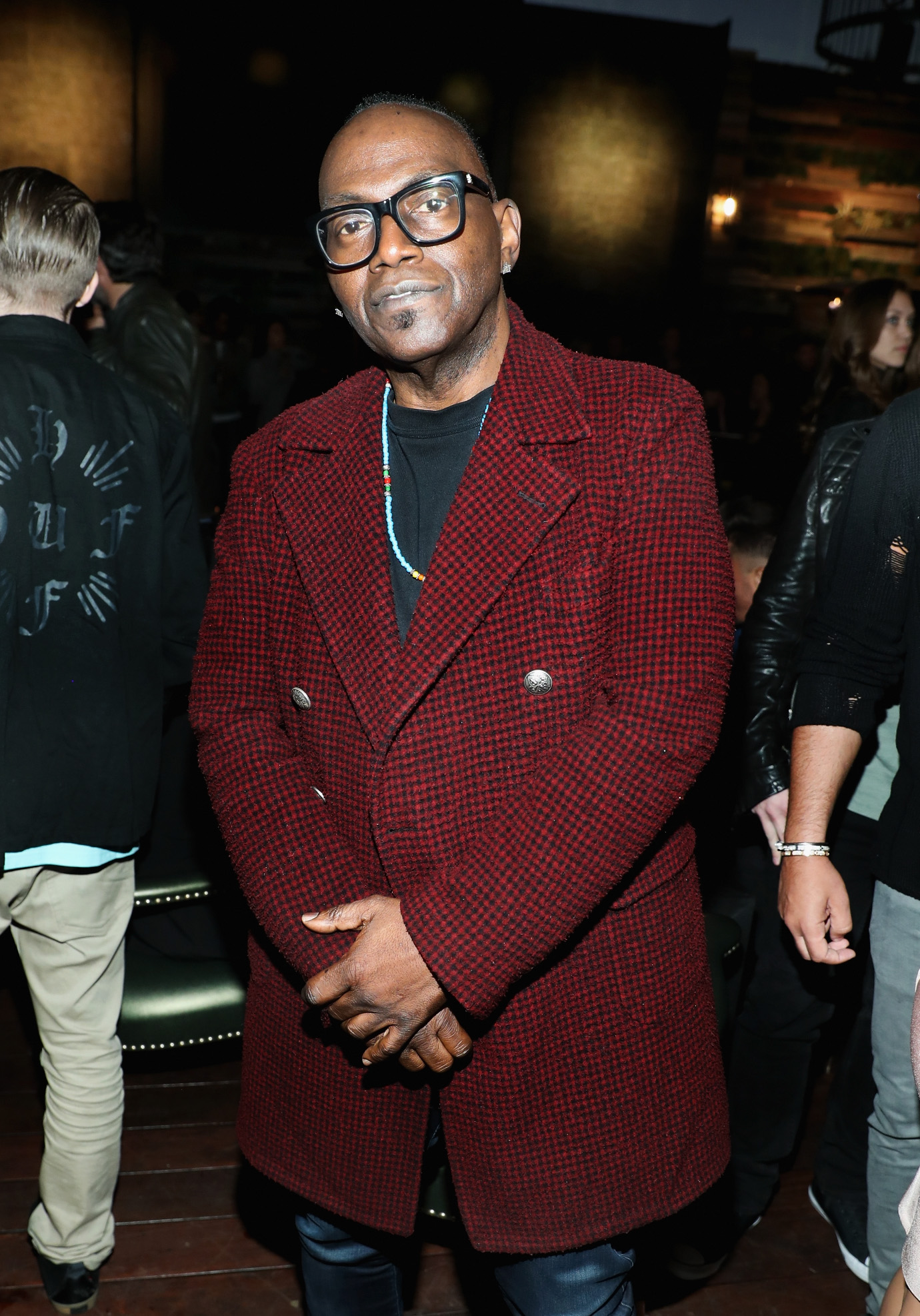 Randy Jackson makes a stylish entrance in a textured red coat and bold black frames while attending an upscale restaurant opening.