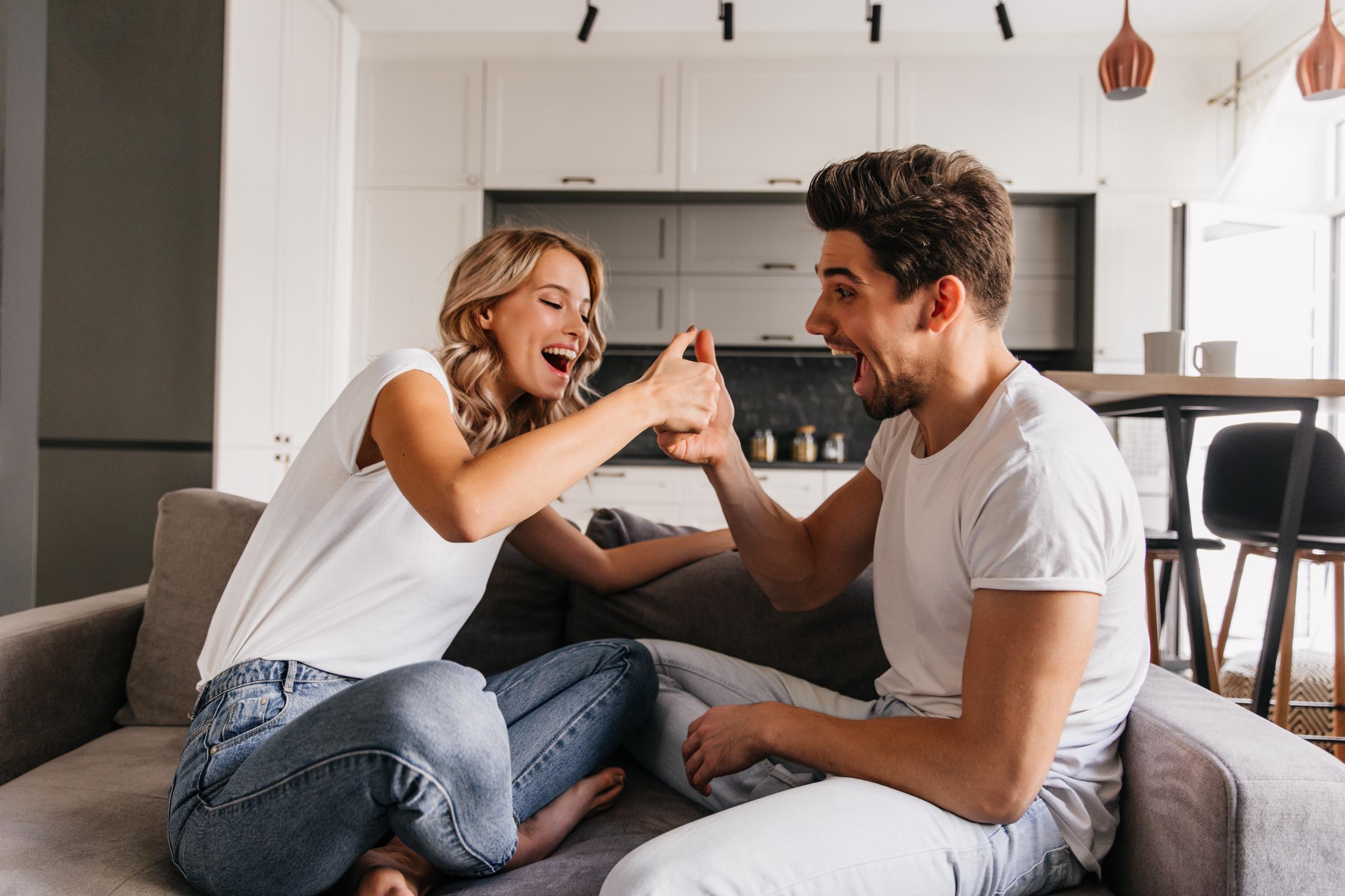 A couple sitting on the couch and laughing | Source: Freepik