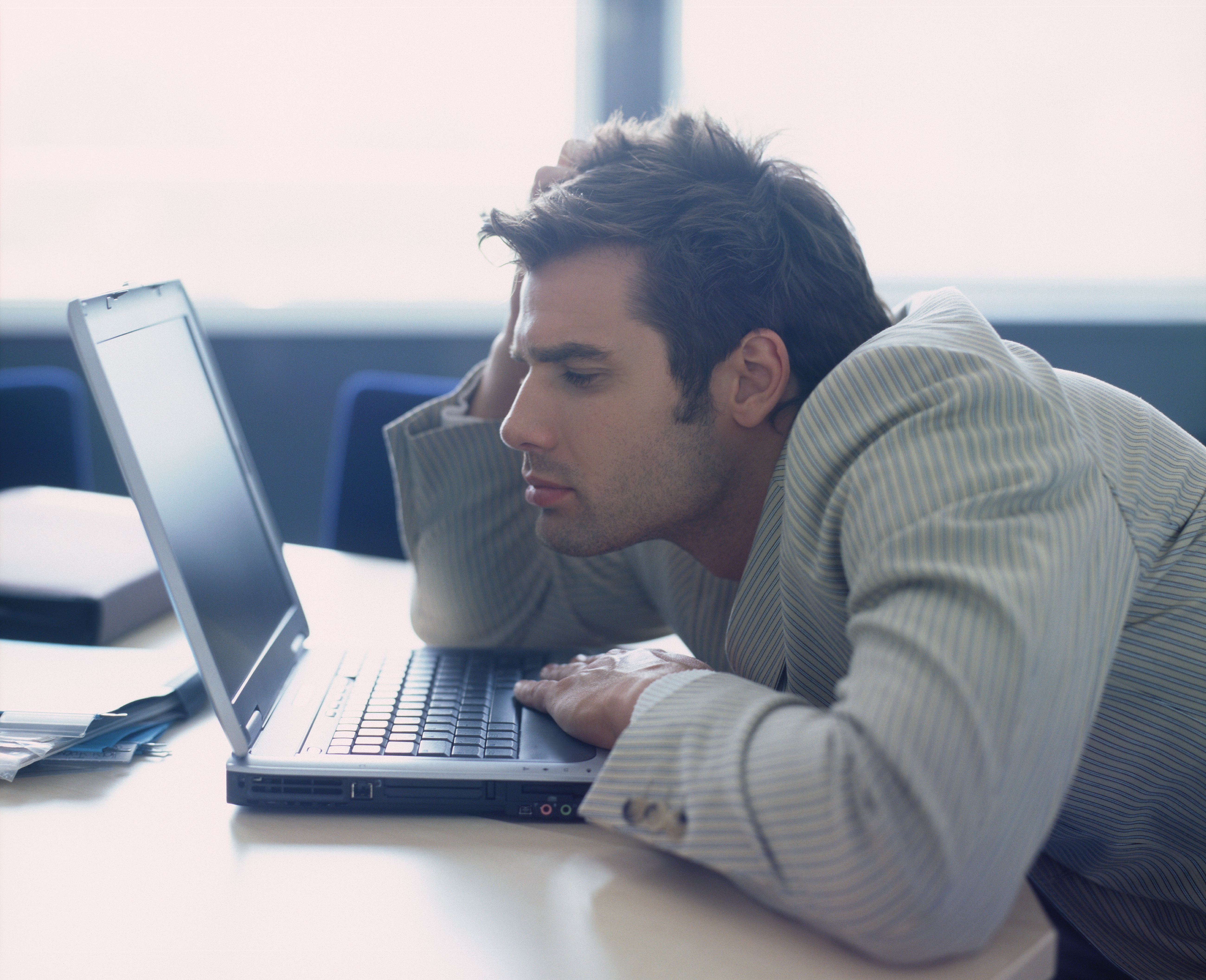 A man slouching over his laptop | Source: Shutterstock
