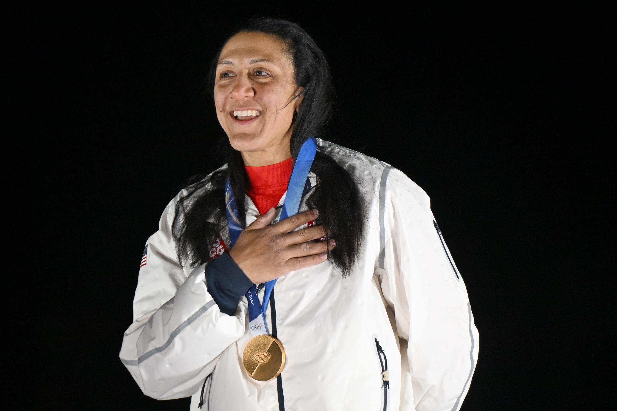 Elana Meyers Taylor stands with her gold medal, hand over her heart, during the medal ceremony at the 2026 Winter Olympics in Cortina d'Ampezzo, Italy | Source: Getty Images