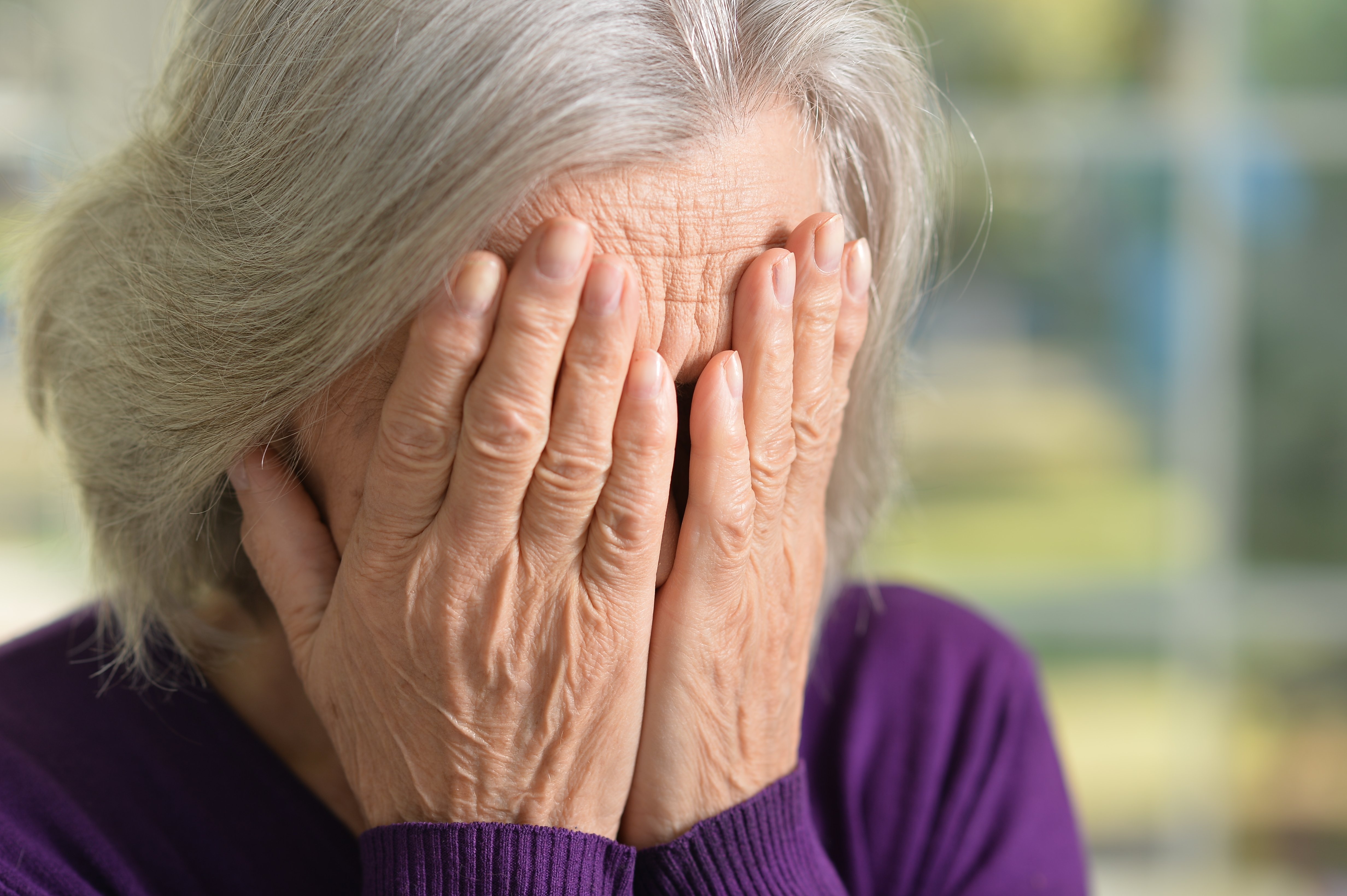 Mujer mayor tapando su rostro con sus manos. | Foto: Shutterstock