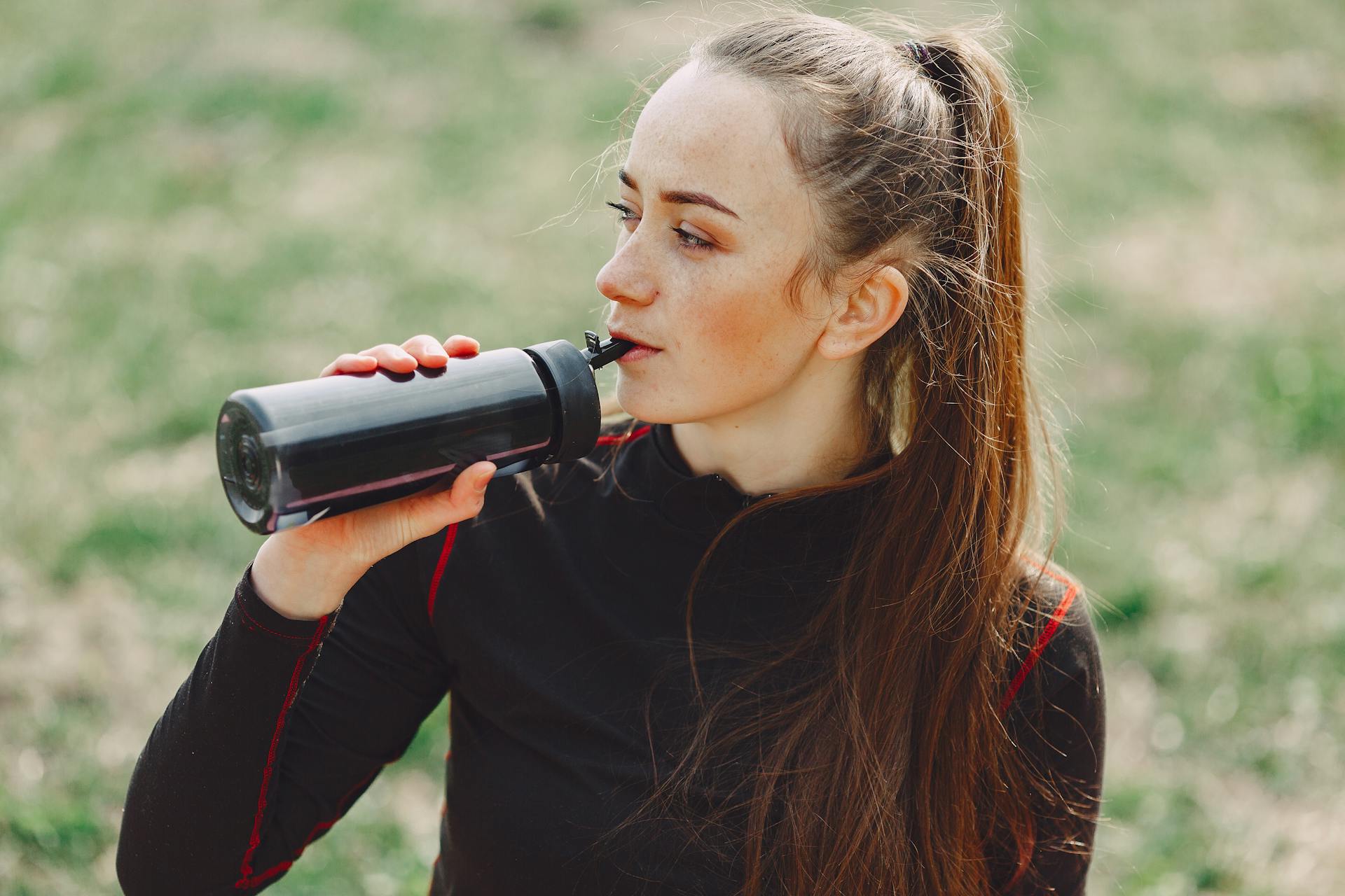 A woman drinking water from a water bottle | Source: Pexels
