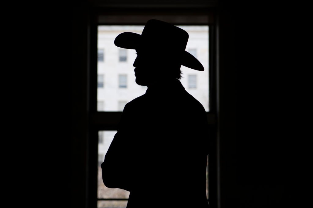 Un homme portant un chapeau de cowboy est vu à l'entrée en fer à cheval du Rayburn Building. |Photo : Getty Images