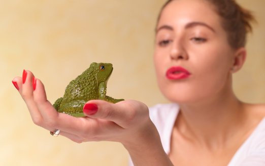 Young woman blowing a kiss to a frog. | Photo: Getty Images
