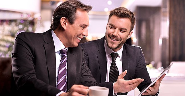Two rich male friends talking and laughing over coffee | Photo: Getty Images