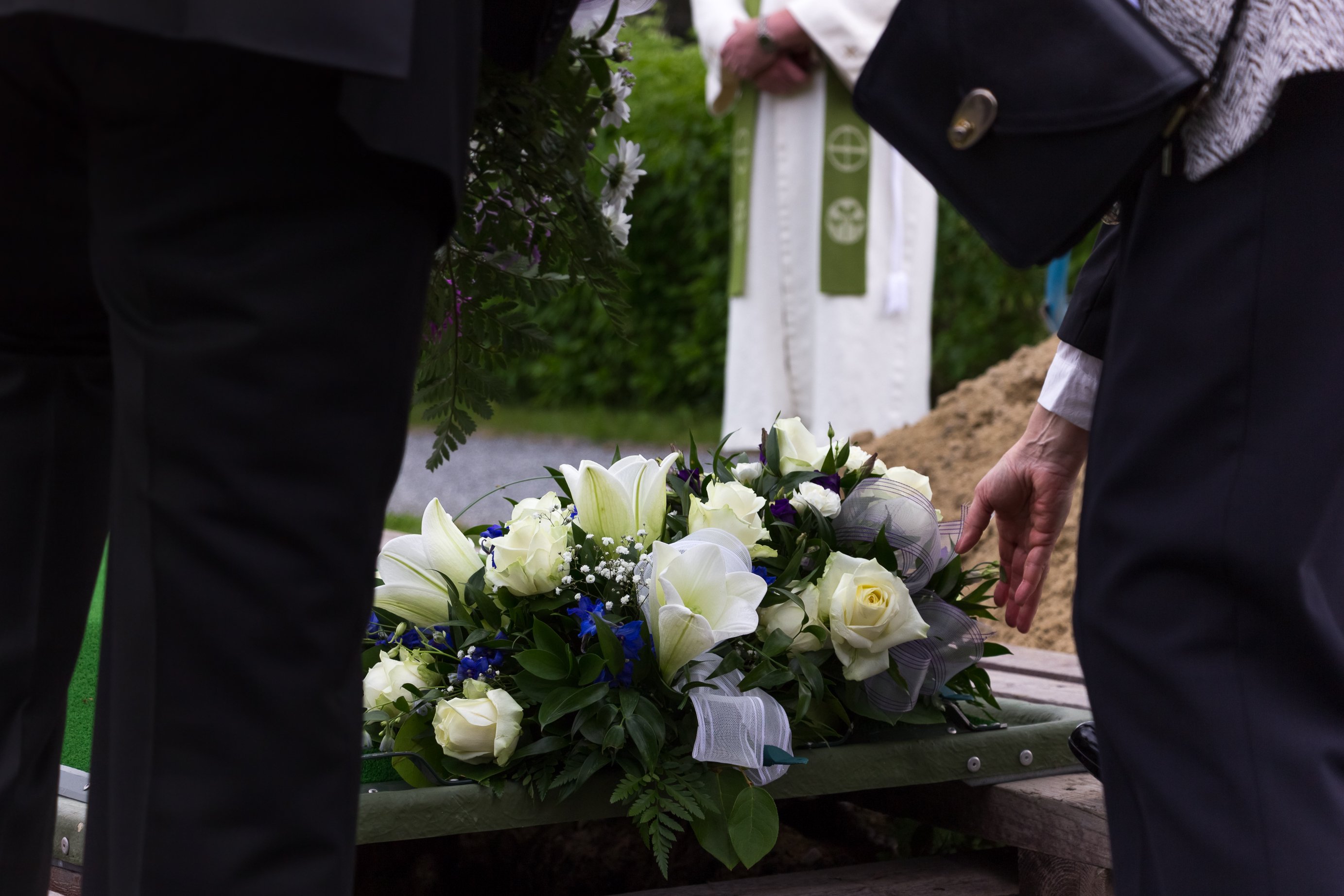Frau, die bei einer Beerdigung Blumen auf ein Grab legt | Quelle: Shutterstock