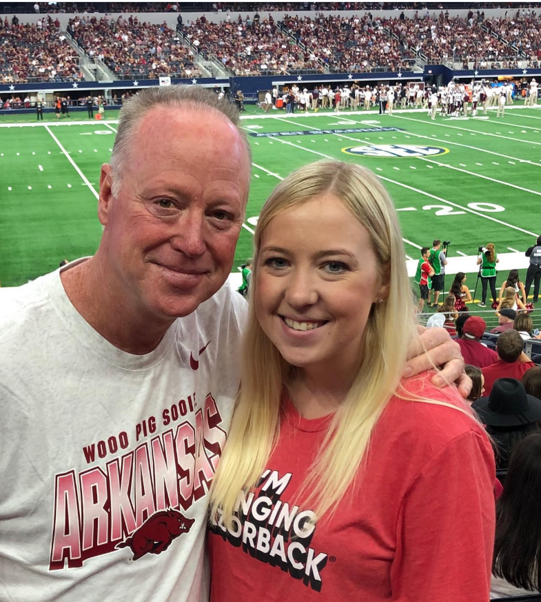 Mike Norris stands arm-in-arm with his daughter Hannah, both smiling in a packed stadium. Dressed in Arkansas gear, they capture a simple, joyful game-day tradition together. | Source: Instagram/iammikenorris