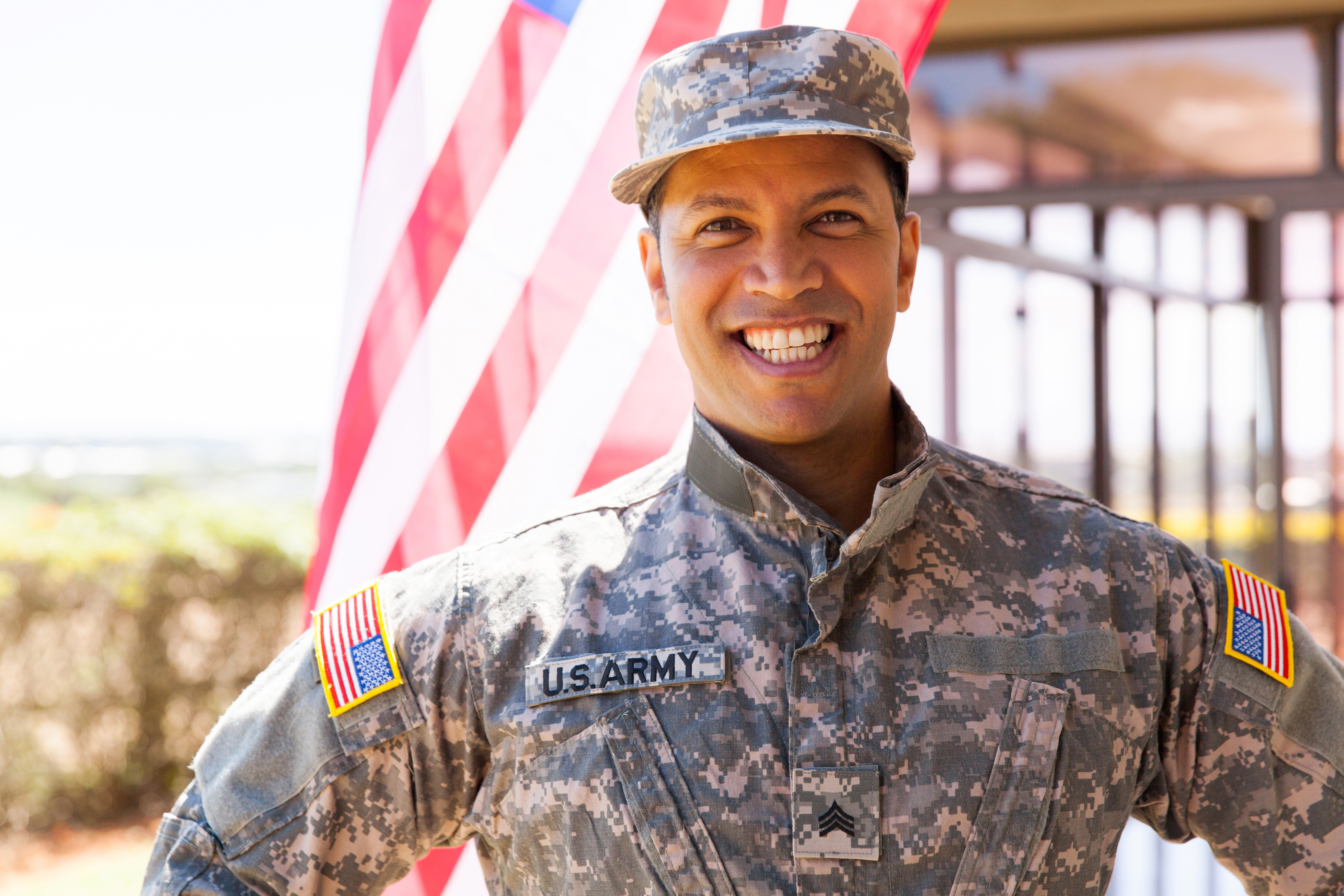 Ein Soldat lächelt mit der US-Flagge im Hintergrund | Quelle: Shutterstock