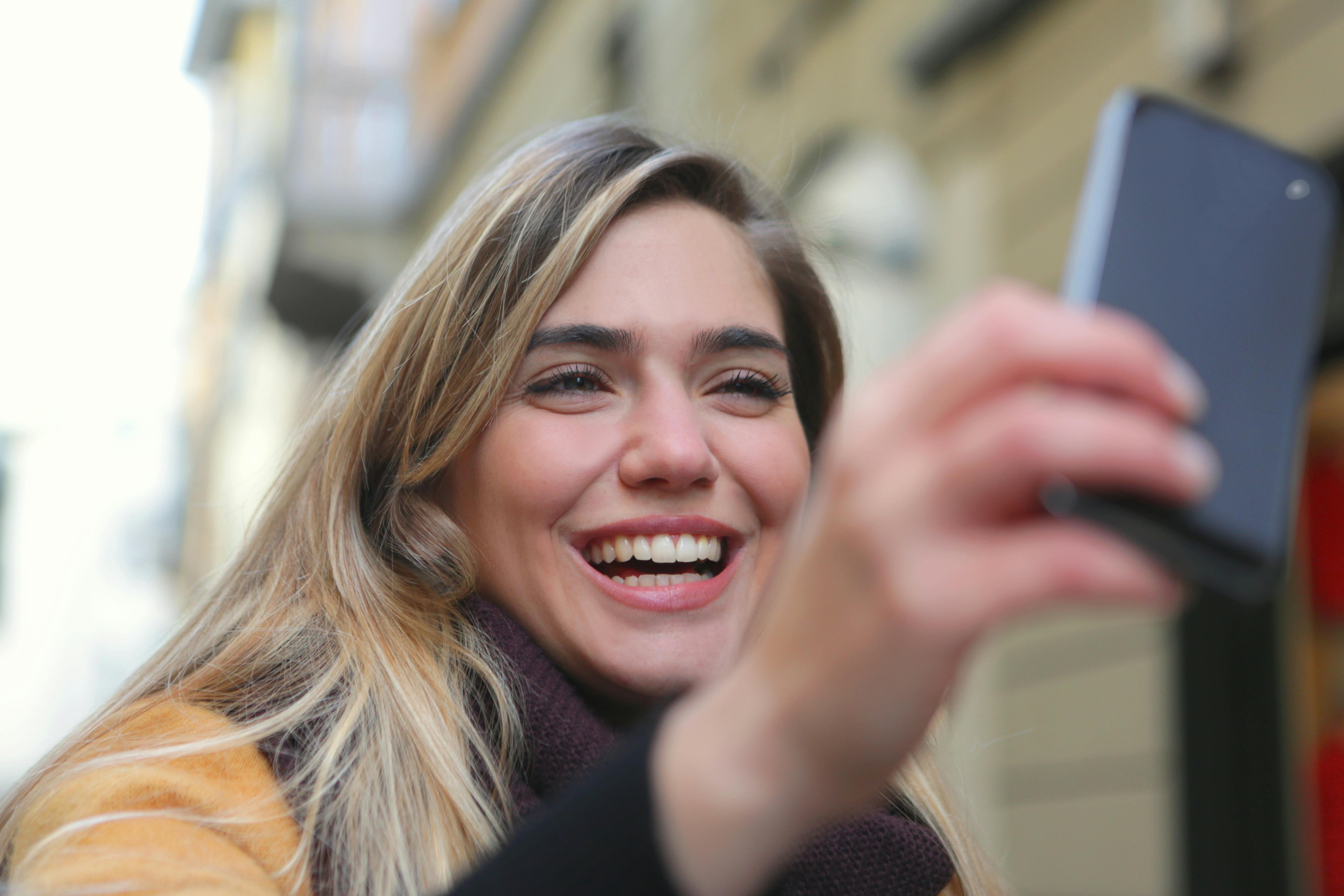 A woman laughing while looking at her phone | Source: Pexels