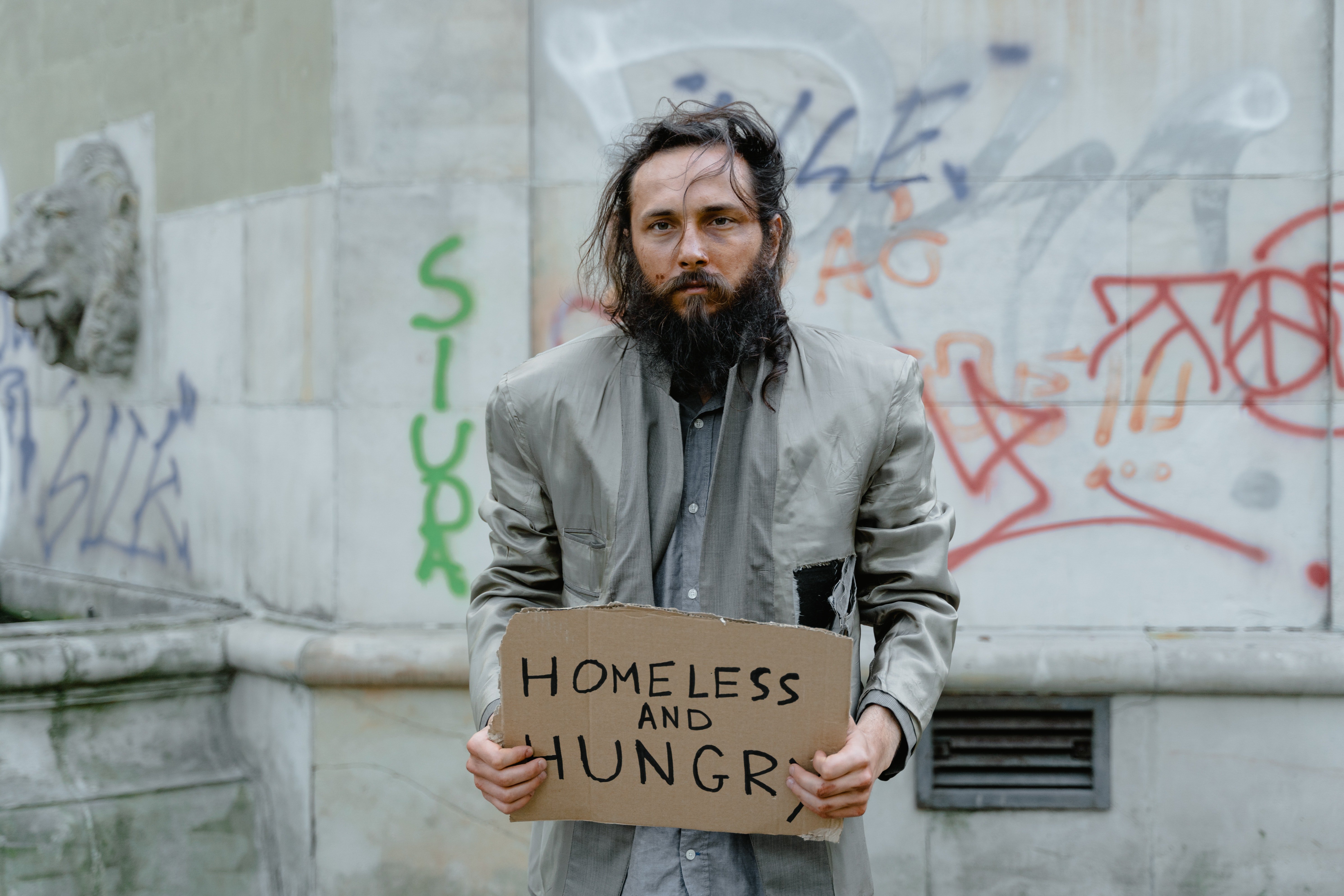 Un indigente con un cartel en su mano. | Foto: Pexels