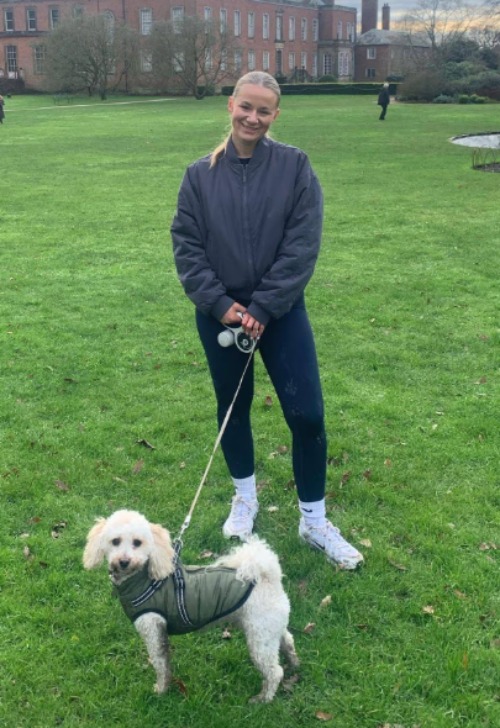 A photo of Lucy Harrison smiling for the camera with a dog, posted on February 11, 2026. | Source: Facebook/RSVP Magazine
