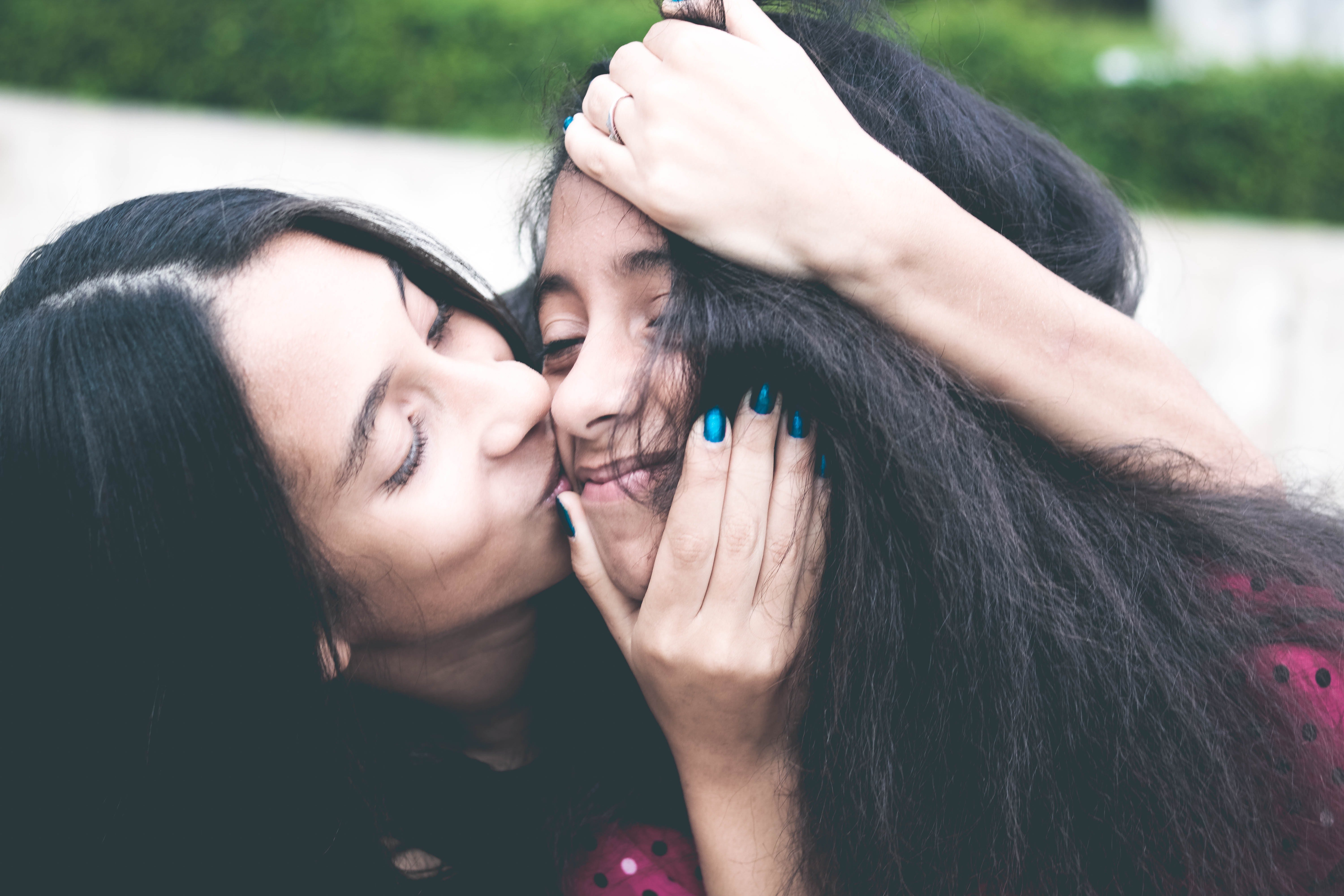 Una madre da un beso a su hija adolescente. | Foto: Pexels