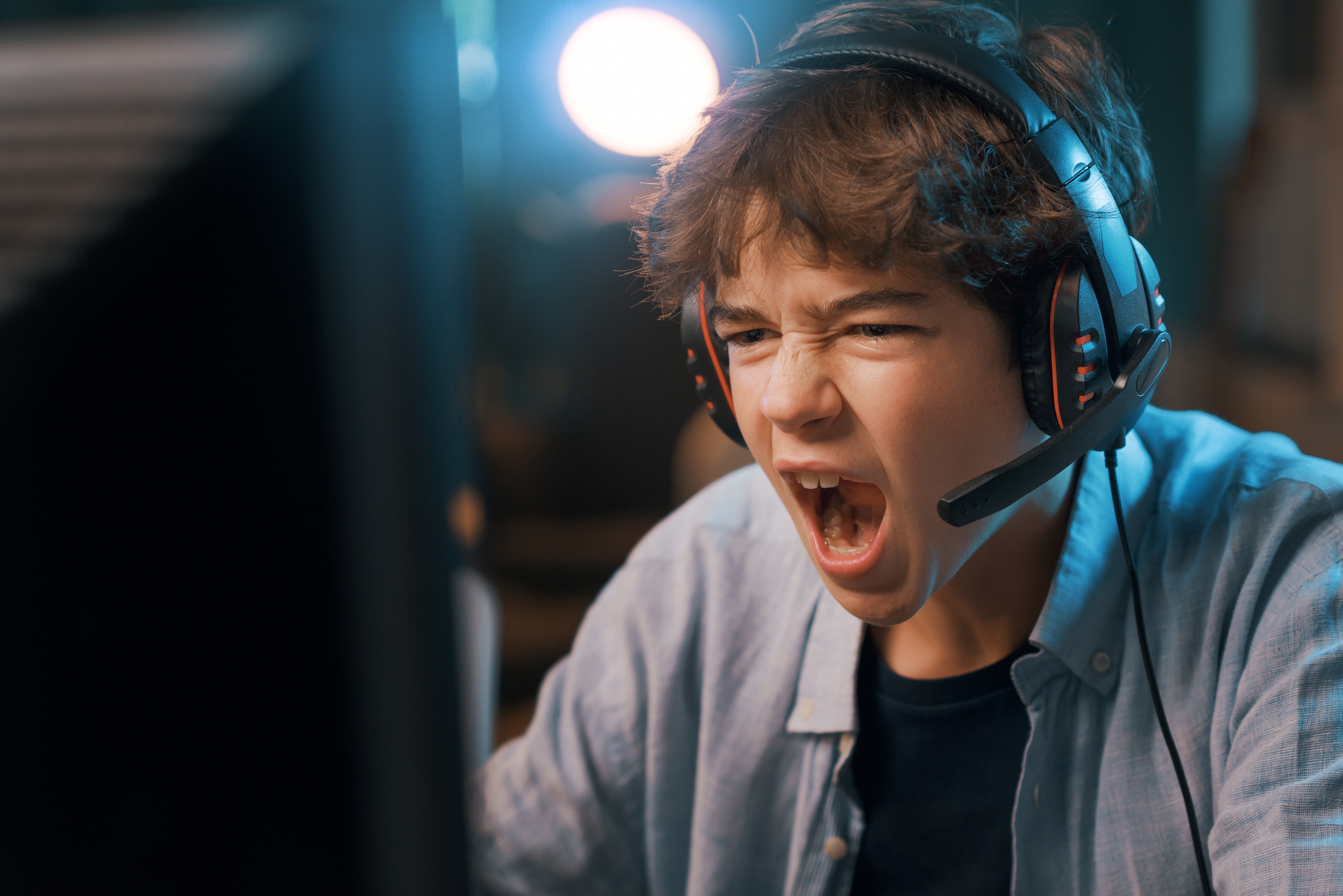 Ein wütender Junge schreit in sein Computer-Headset│Quelle: Shutterstock