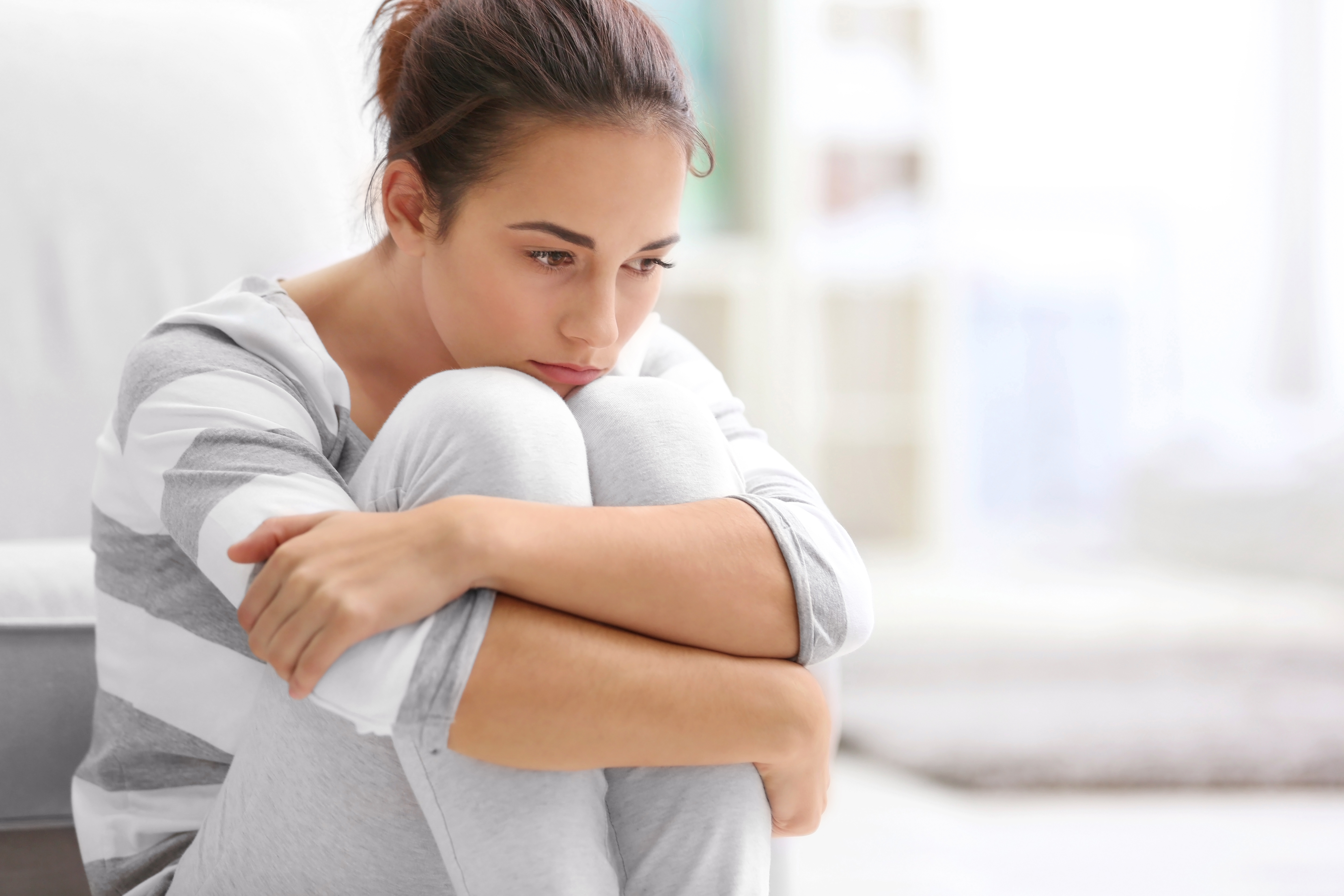A woman hugging her knees in deep thought | Source: Shutterstock