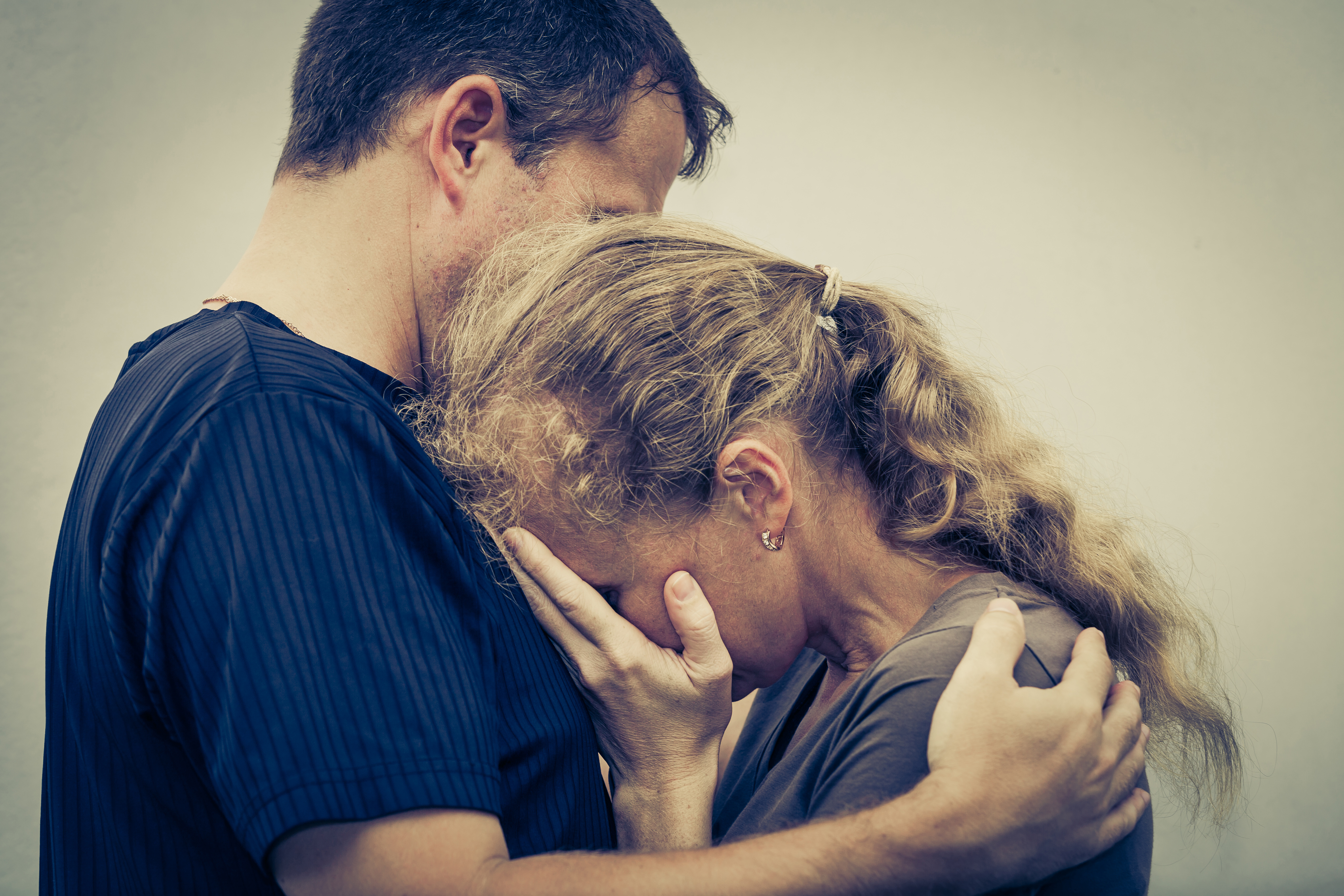 A crying woman hugging her husband | Source: Shutterstock