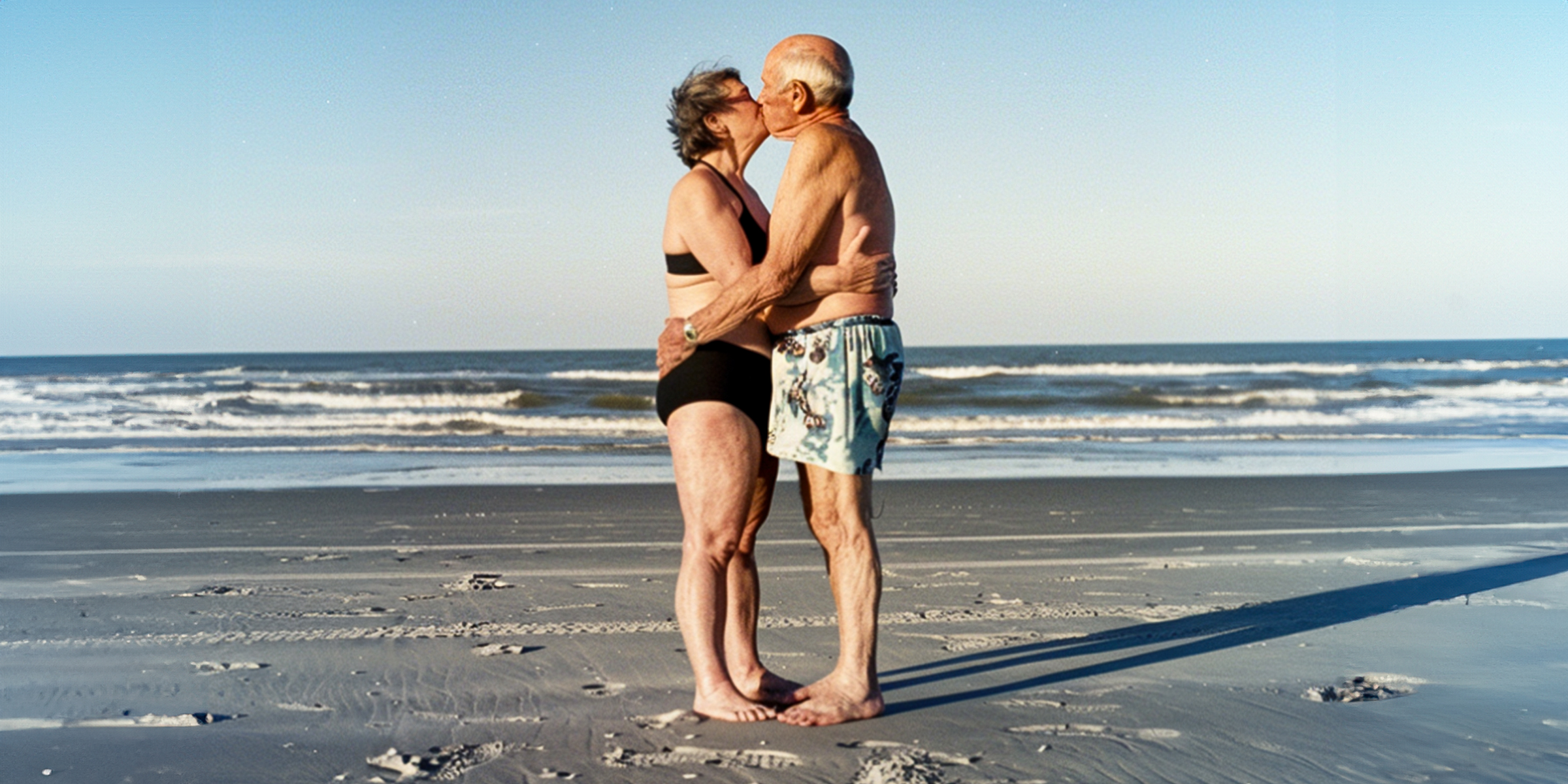 An older couple kissing on the beach | Source: AmoMama