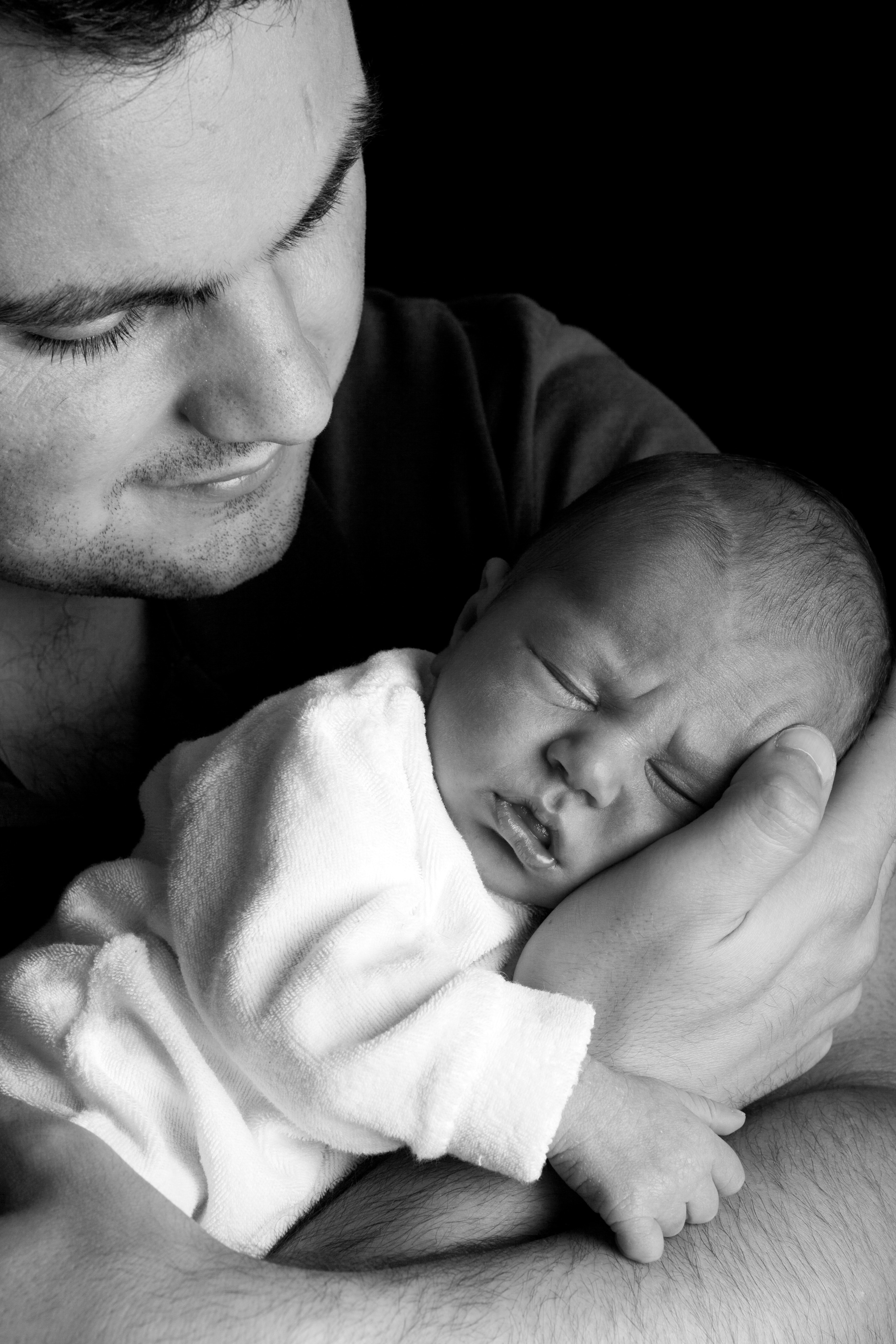 Hombre joven sostiene a un bebé en sus brazos. | Foto: Pexels