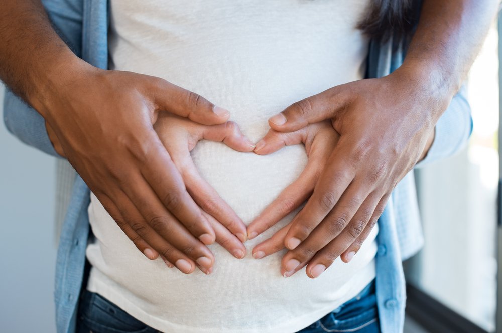  Mujer embarazada y esposo amoroso abrazando la barriga en casa. Corazón de manos por pareja multiétnica en vientre embarazado. I Foto: Shutterstock