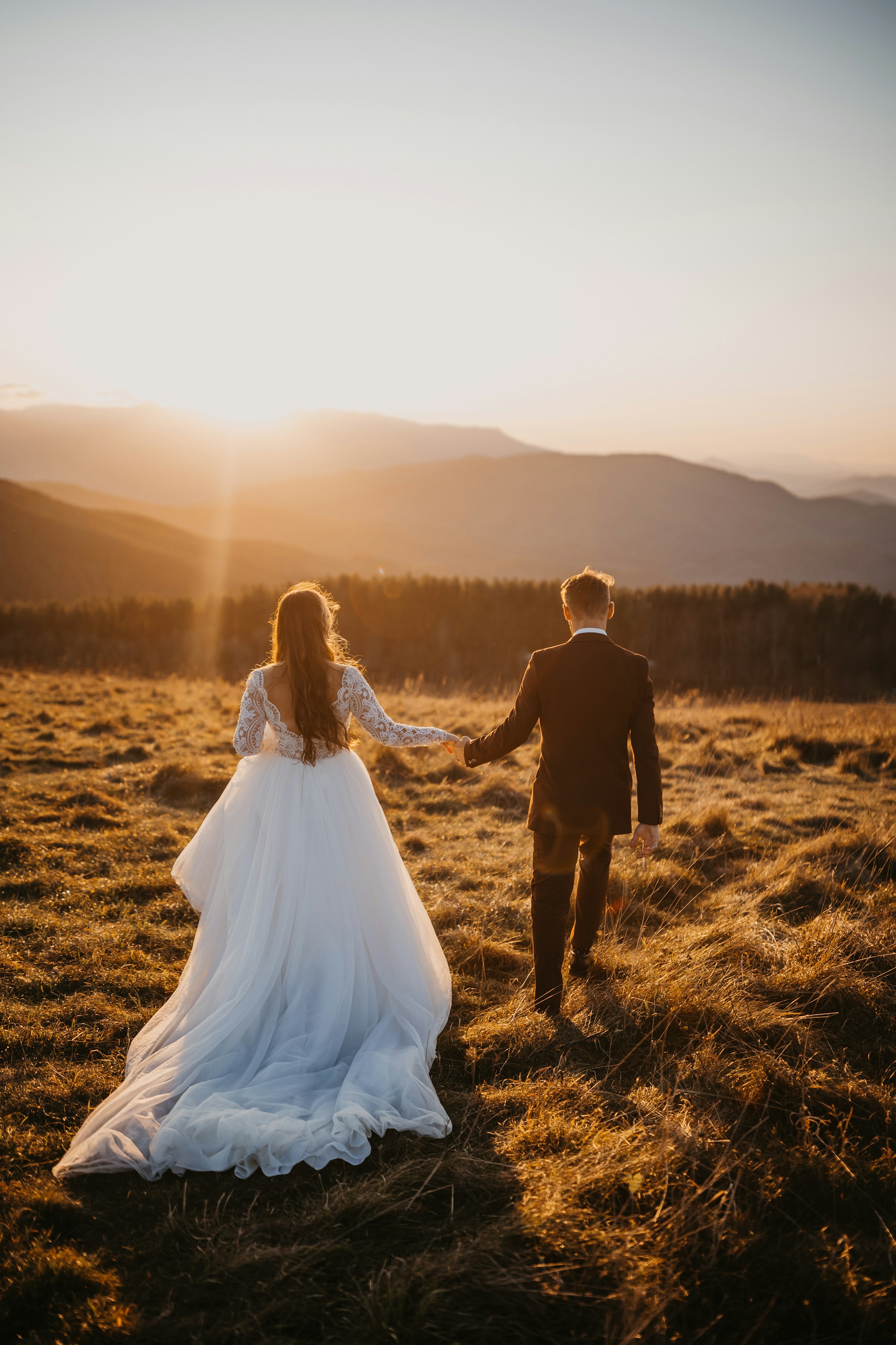 A bride and groom passing through a field during the golden hour | Source: Unsplash