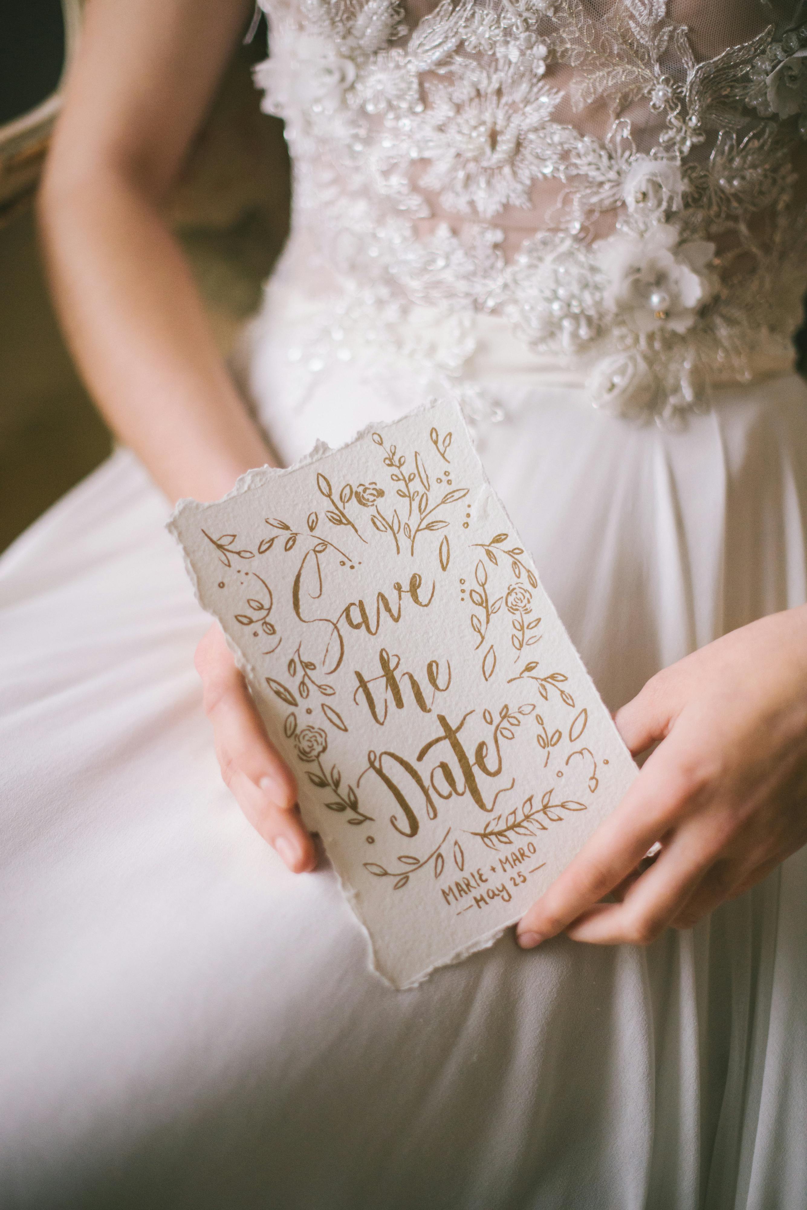 A woman in a white dress holding a wedding invitation | Source: Pexels