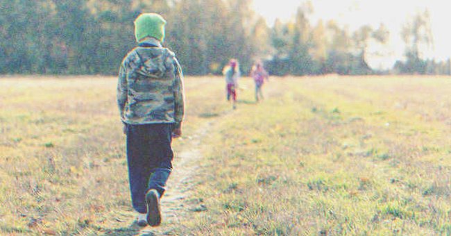 Un niño camina por un parque, mientras dos niñas corren a lo lejos. | Foto: Shutterstock