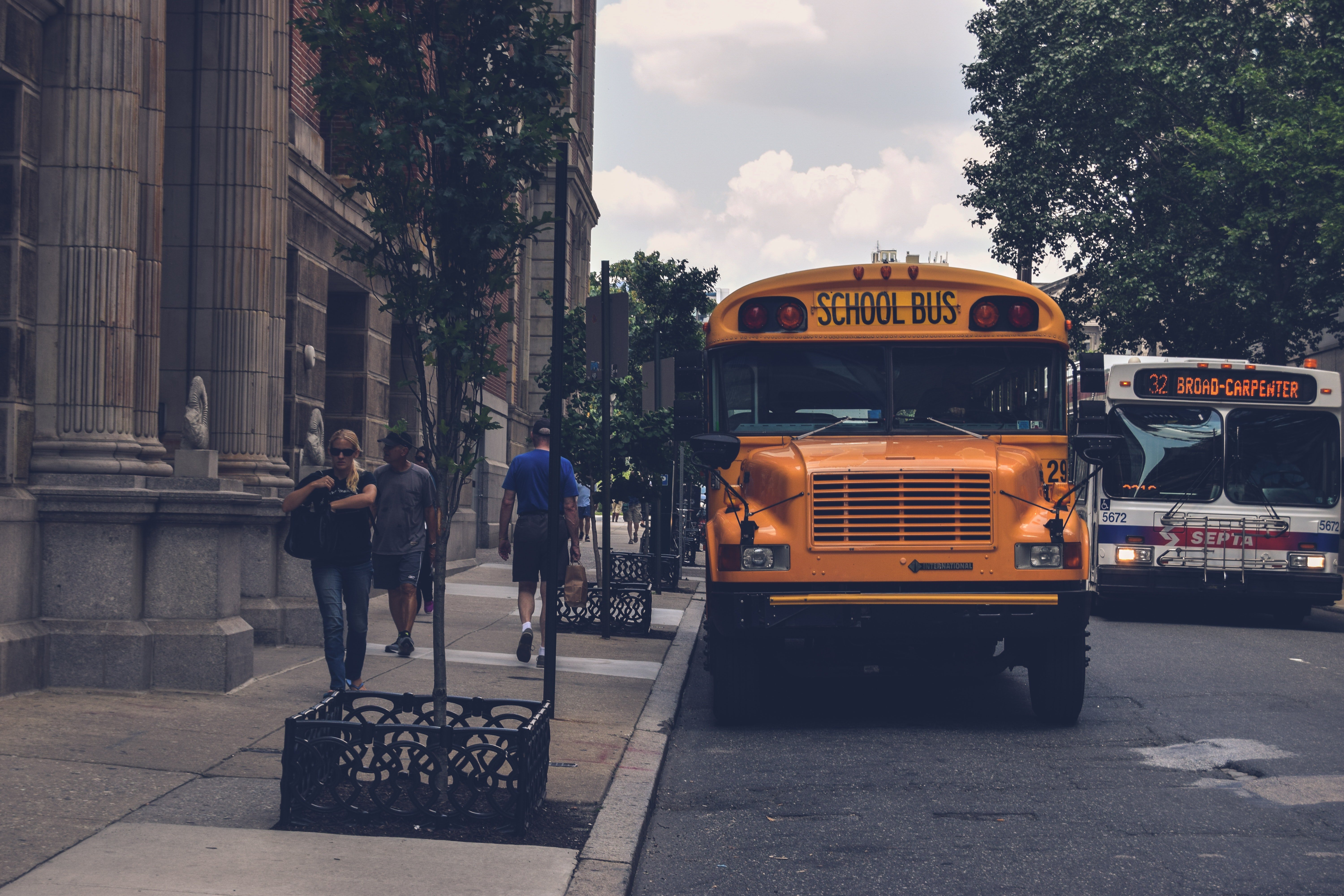 Yellow school bus beside a concrete building. | Photo: Pexels