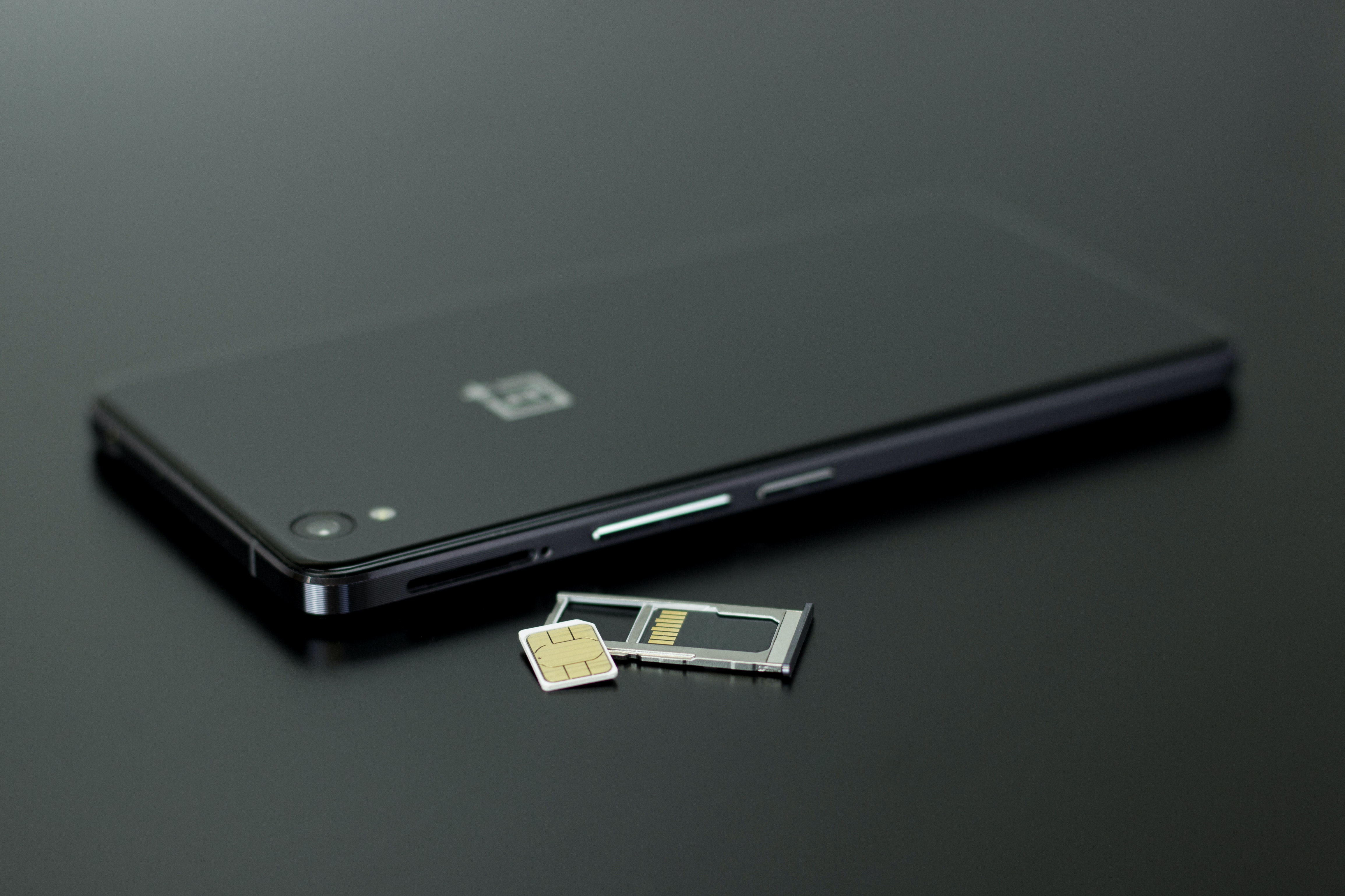 A black phone and a sim on a black table top | Source: Pexels