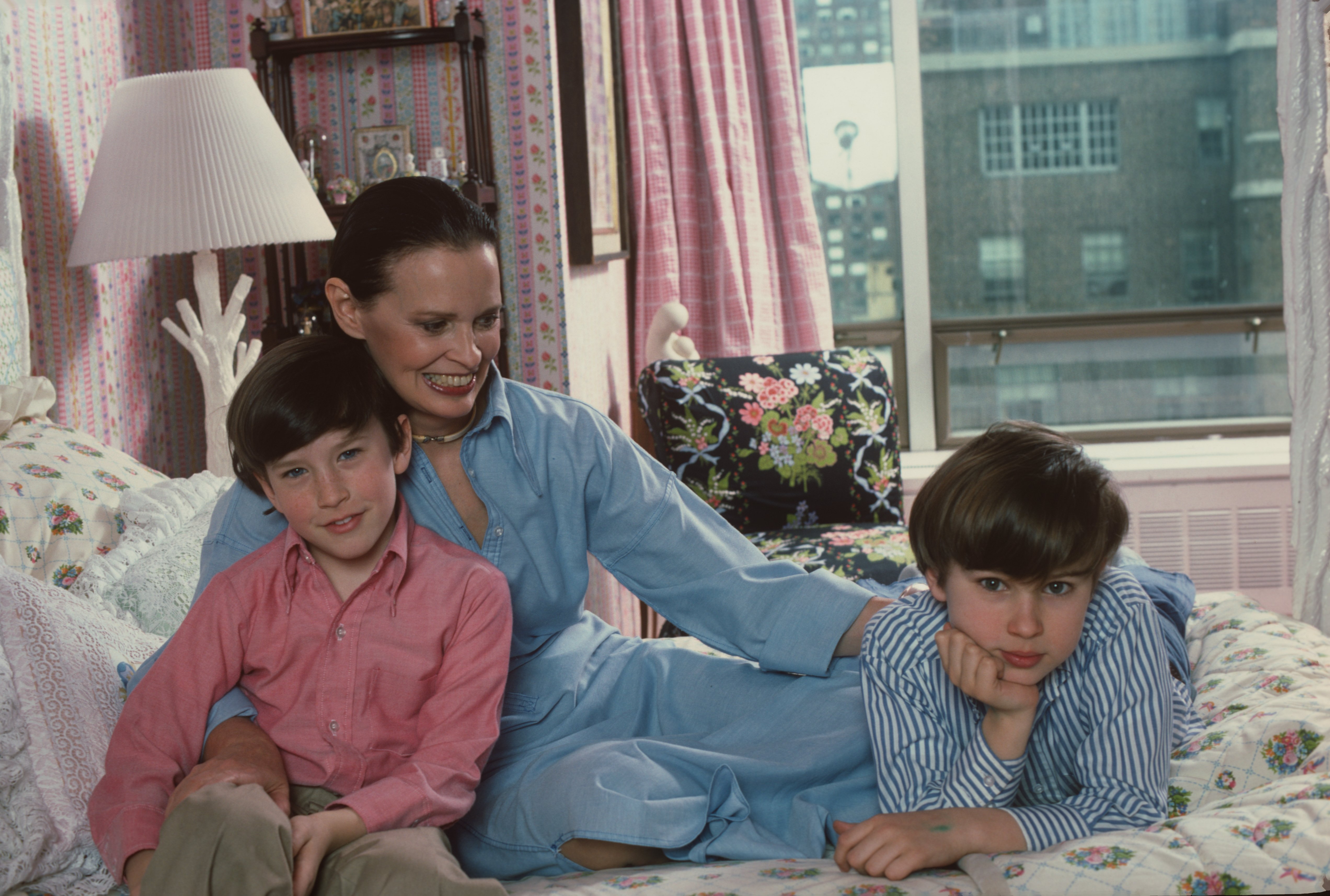 Gloria Vanderbilt poses with her two sons Anderson Cooper and Carter Vanderbilt Cooper on her bed in their apartment in the UN Towers, New York, March 1976. | Source: Getty Images