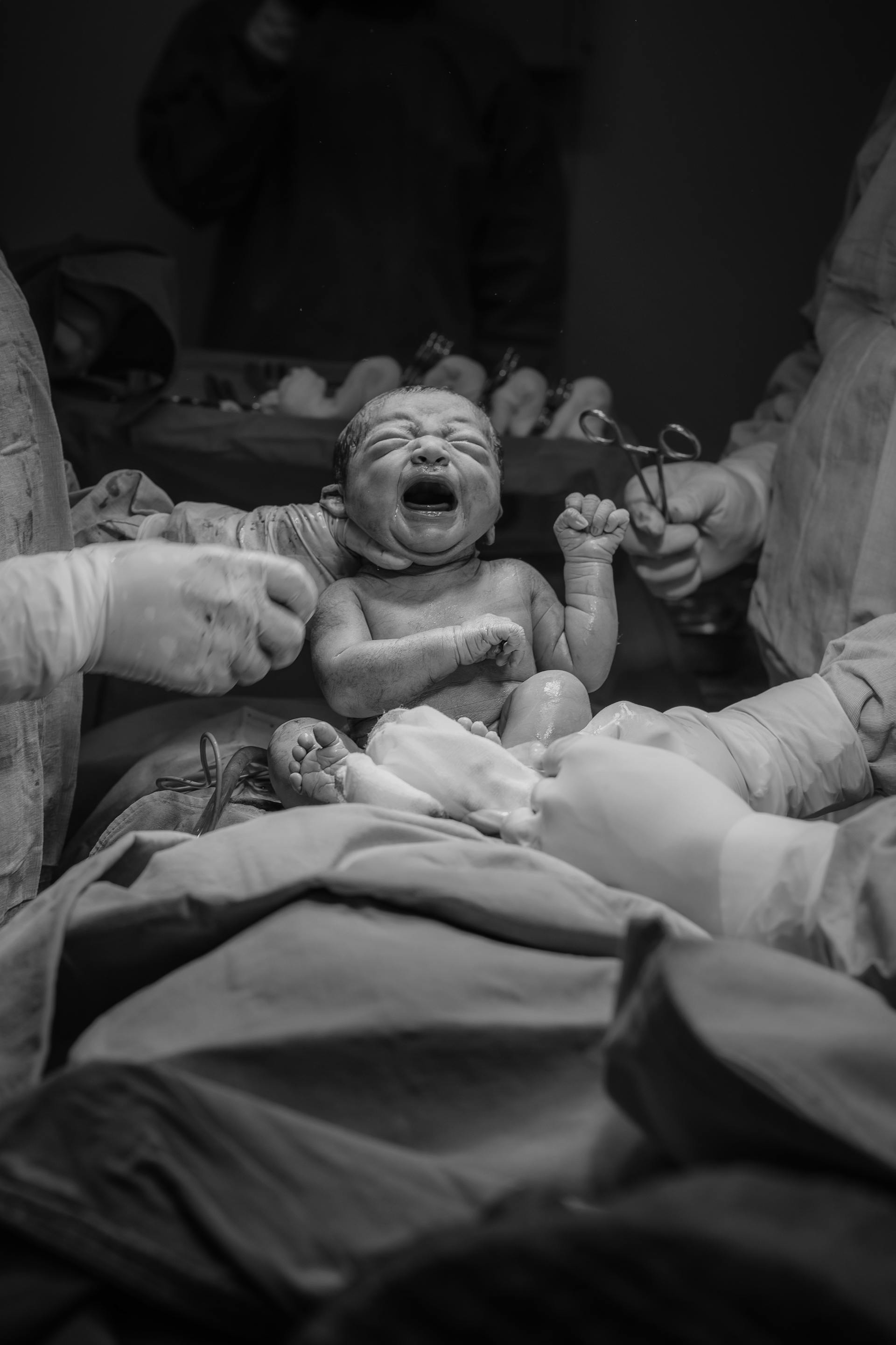A grayscale photo of hospital staff holding a newborn baby | Source: Pexels