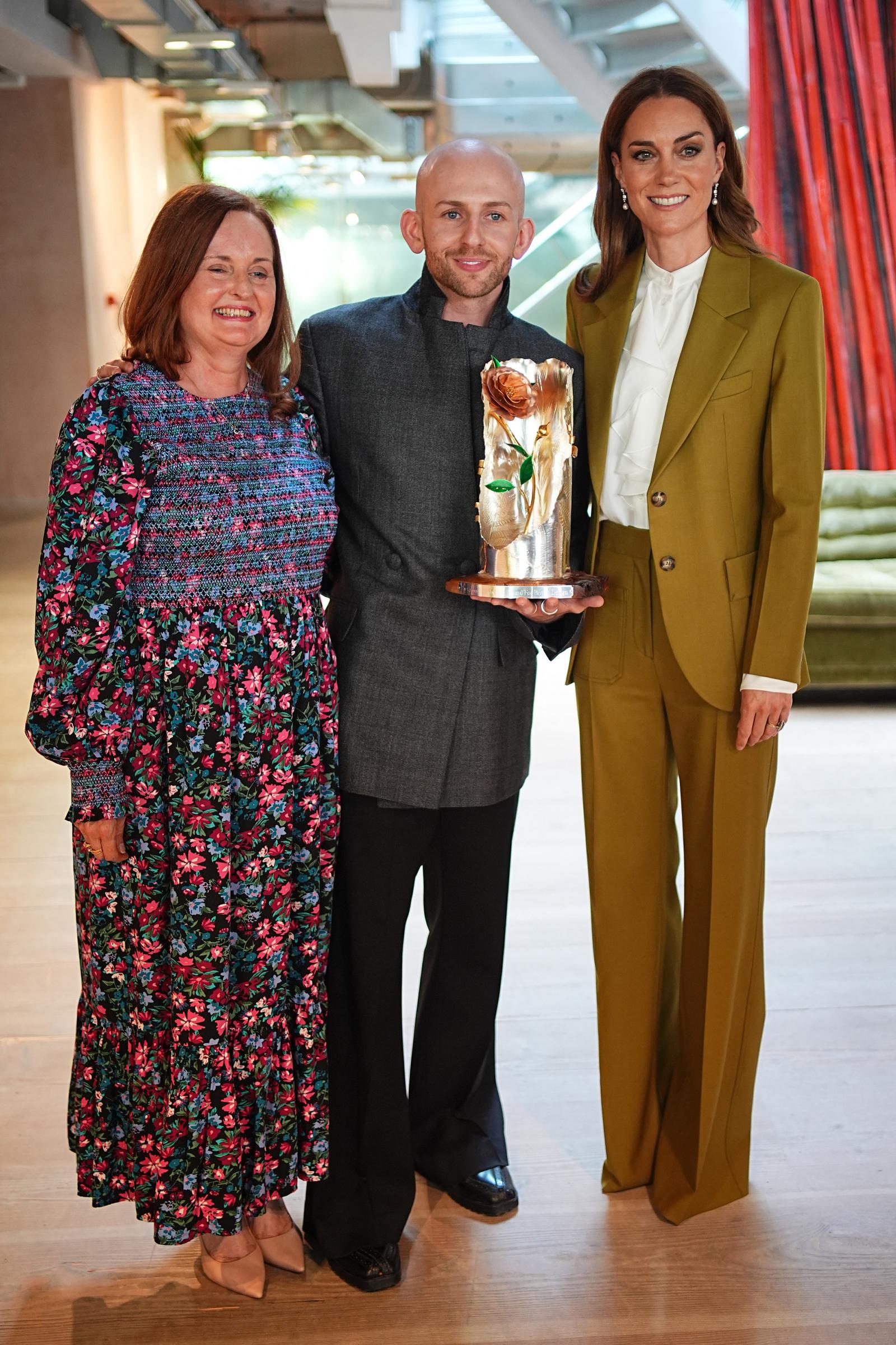 Catherine and Patrick McDowell’s mother stand on either side of him, all wearing proud, happy smiles as he holds his trophy after receiving the Queen Elizabeth II Award for British Design at The British Design Council, 180 Studios in central London.