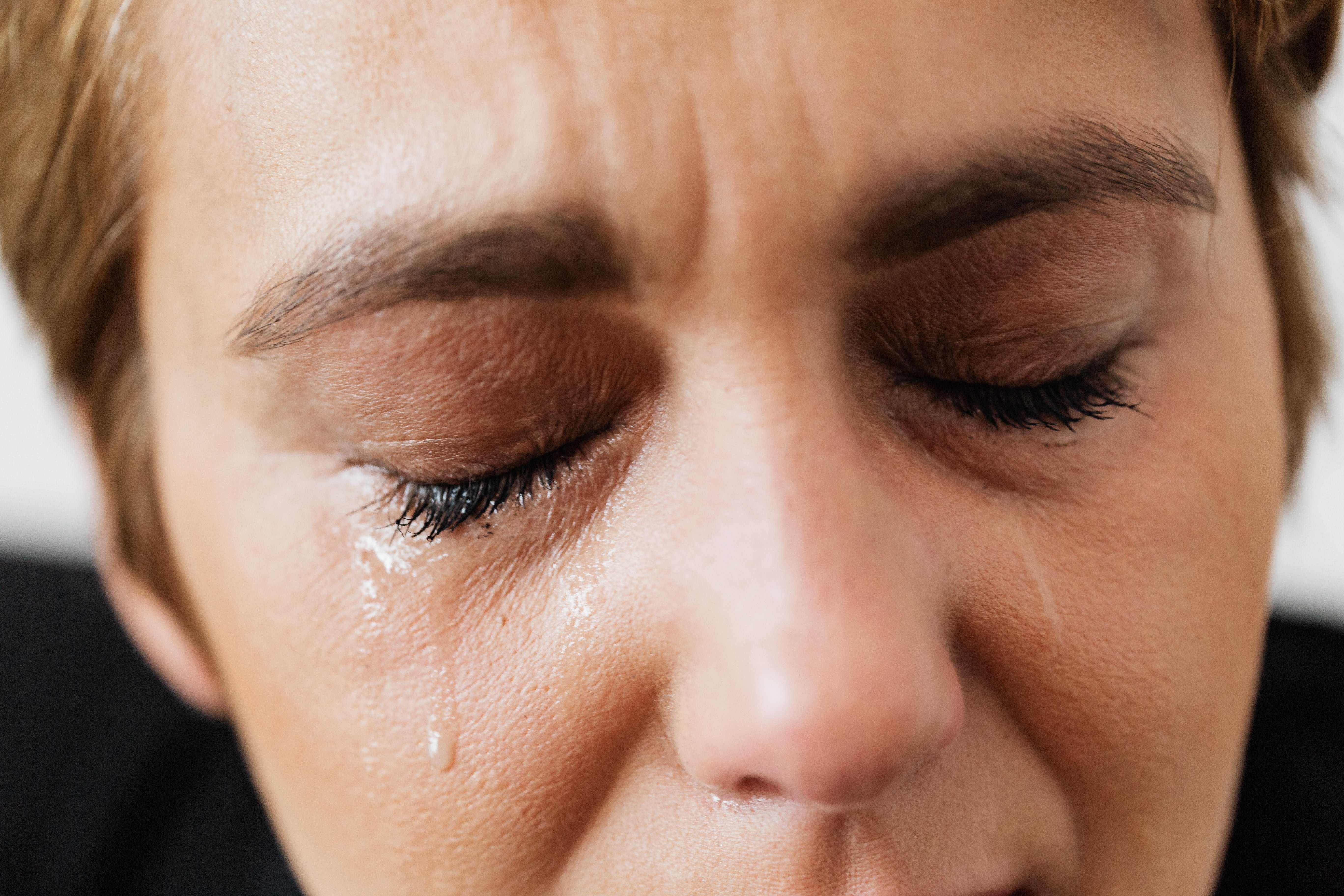 A woman has tears running down her face with her eyes closed | Source: Pexels
