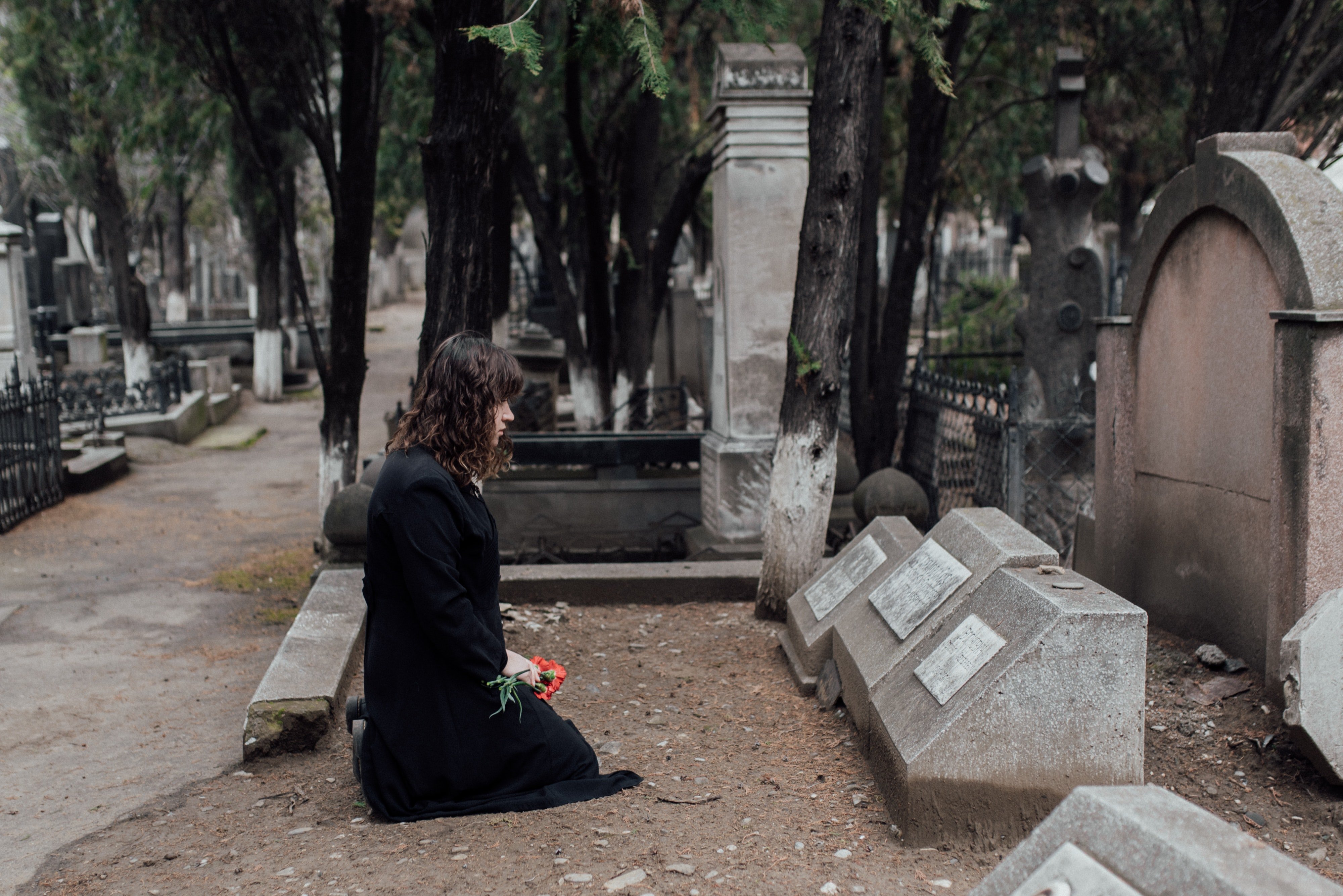 Mujer arrodillada frente a una tumba. | Foto: Pexels