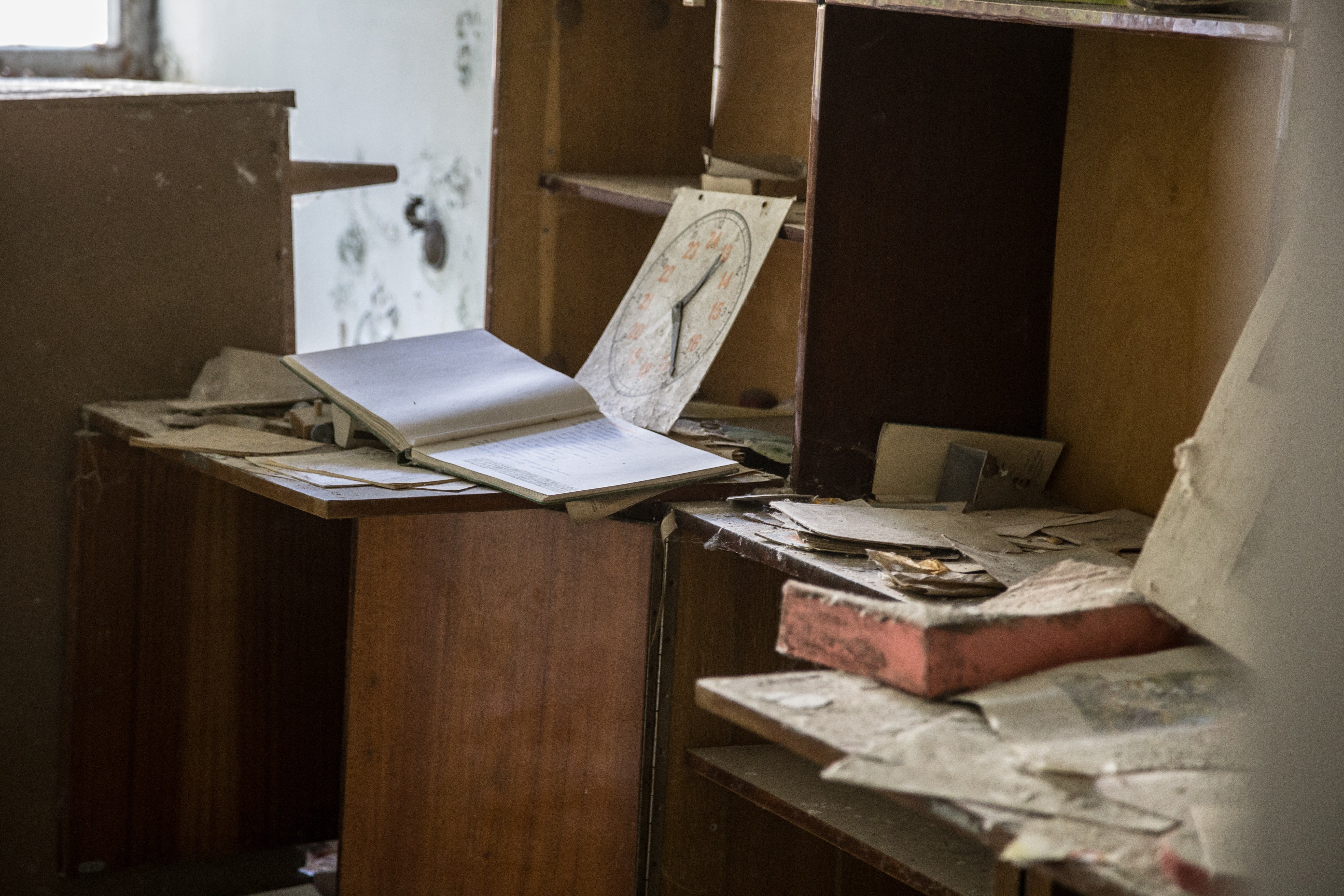 Open book on desk beside piles of paper | Photo: Pexels