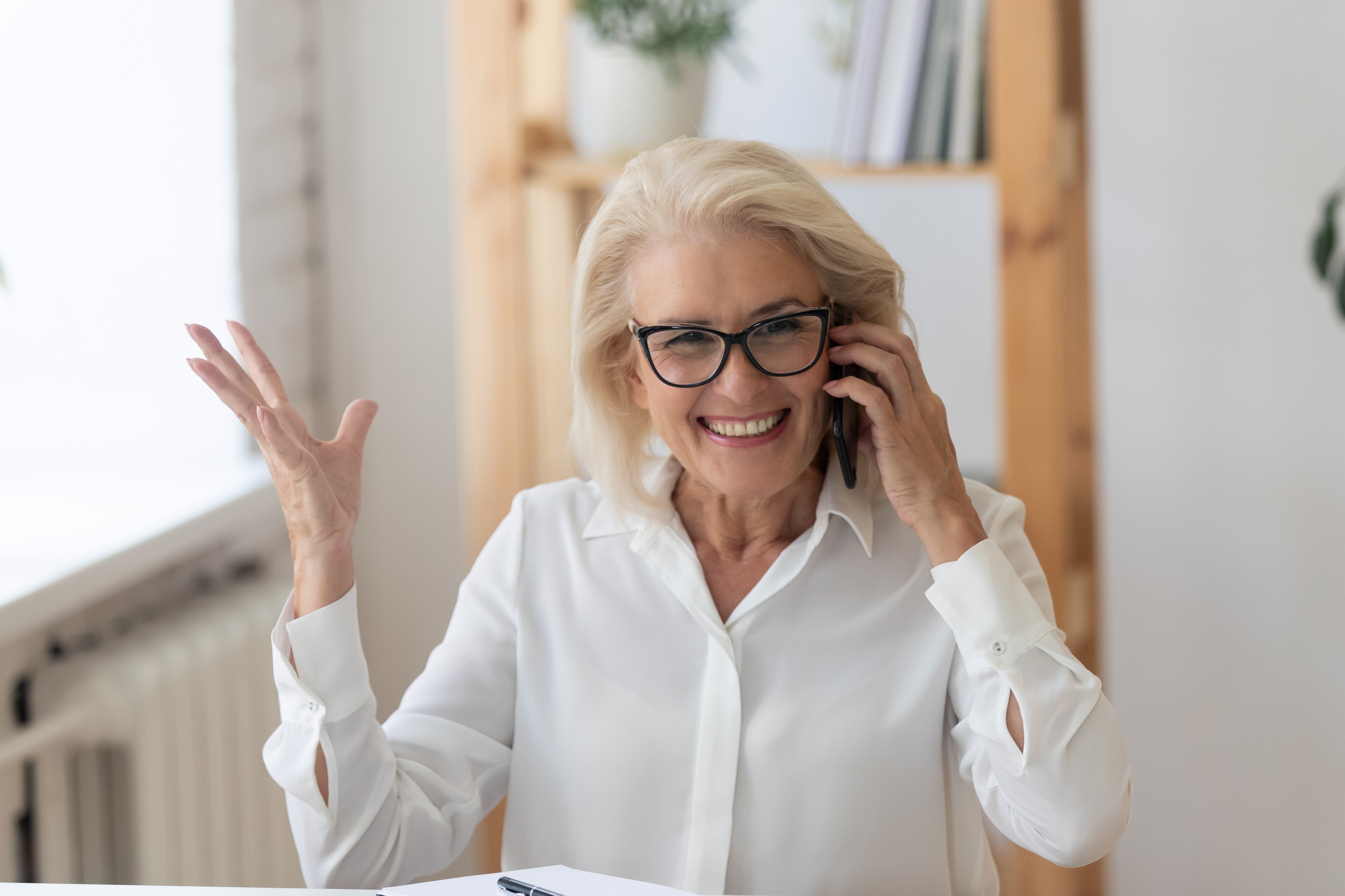 Elderly woman smiling while talking on the phone. │Source: Shutterstock