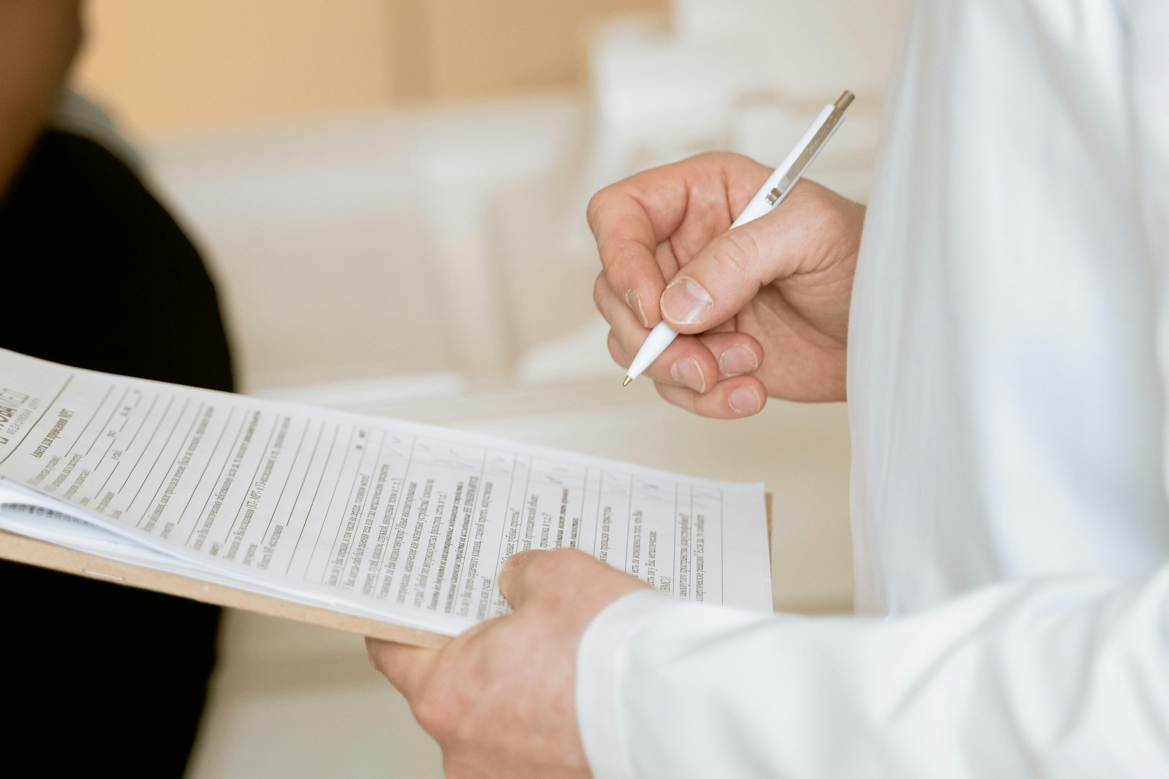 A doctor holding a clipboard and pen | Source: Pexels