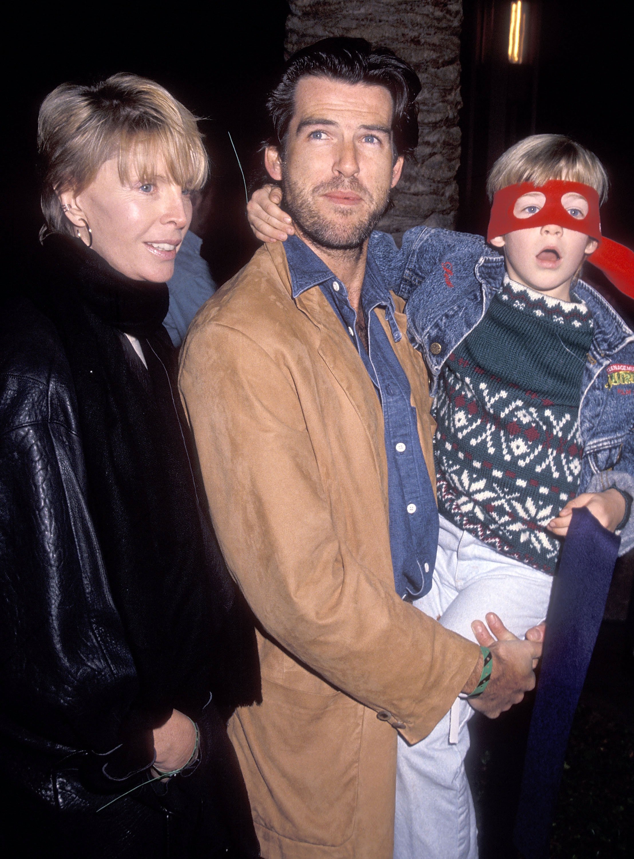 Actor Pierce Brosnan, wife Cassandra Harris and son Sean Brosnan attend the Pre-Show Backstage Pizza Party for the Teenage Mutant Ninja Turtle's "Coming Out of Their Shells" Rock & Roll Tour on November 21, 1990 at the Universal Amphitheatre in Universal City, California. | Source: Getty Images