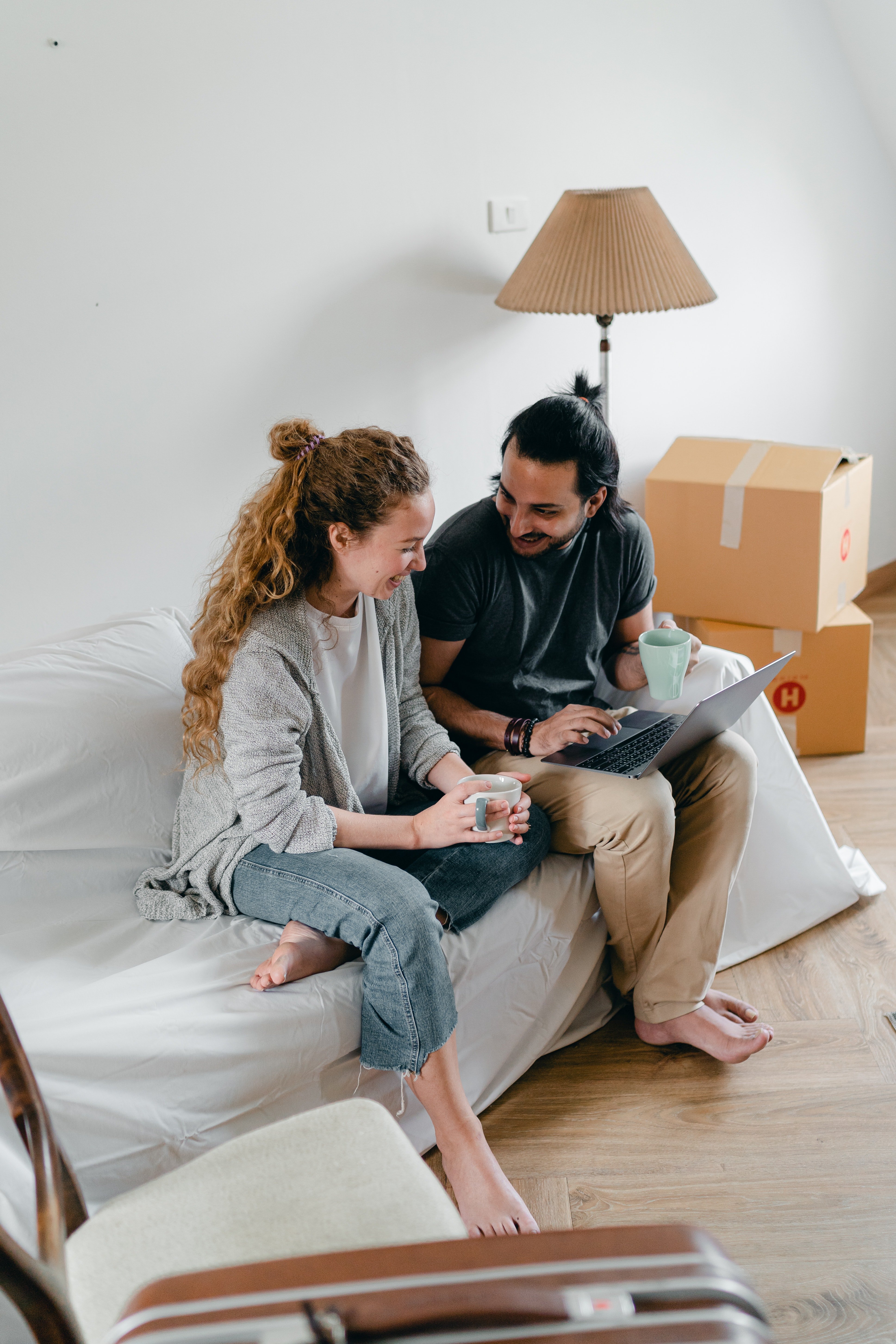 A couple sitting with each other on a couch laughing. | Source: Pexels/  Ketut Subiyanto