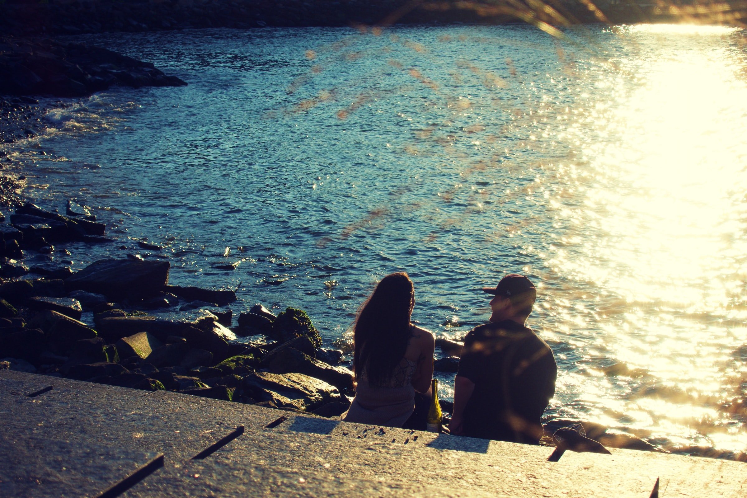 A couple sitting on the rocks near water. | Source: Unsplash