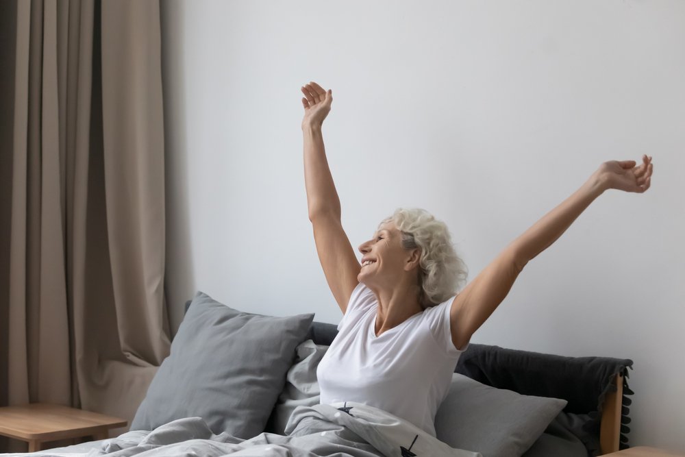 Refreshed middle aged senior woman sitting in bed | Source: Shutterstock