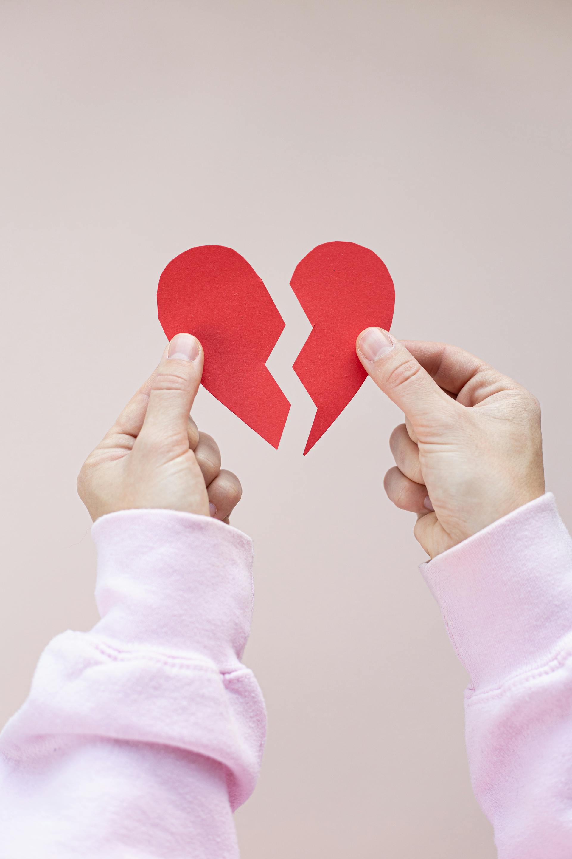 A person holding a broken red paper heart | Source: Pexels