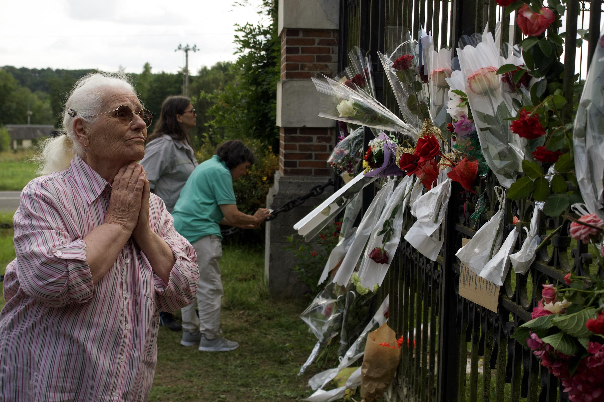 A woman pays tribute as people lay flowers in front of the entrance of the property of Alain Delon, La Brulerie, in Douchy, central France, on August 18, 2024. | Source: Getty Images