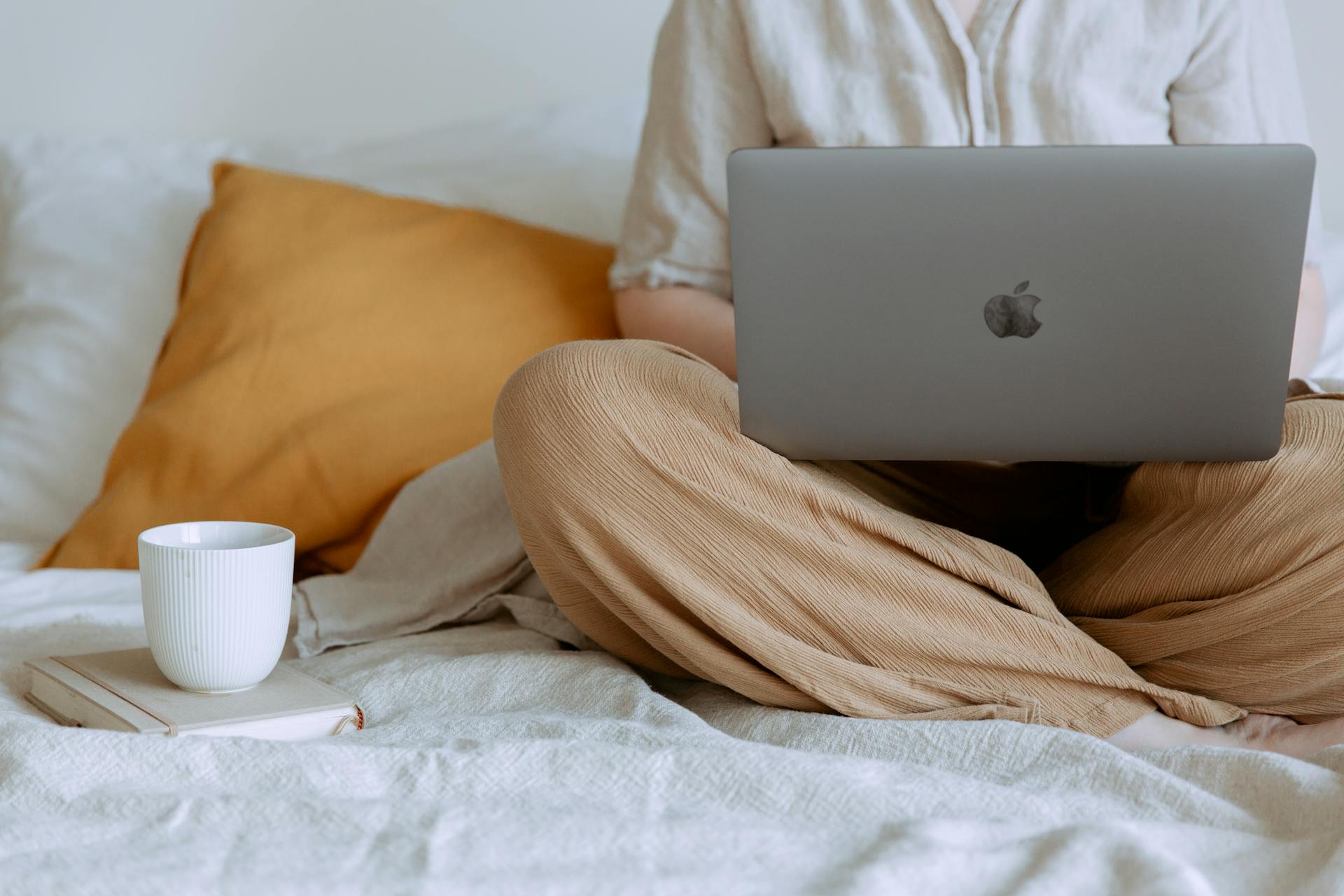 A close-up of a woman using her laptop while sitting on her bed | Source: Pexels