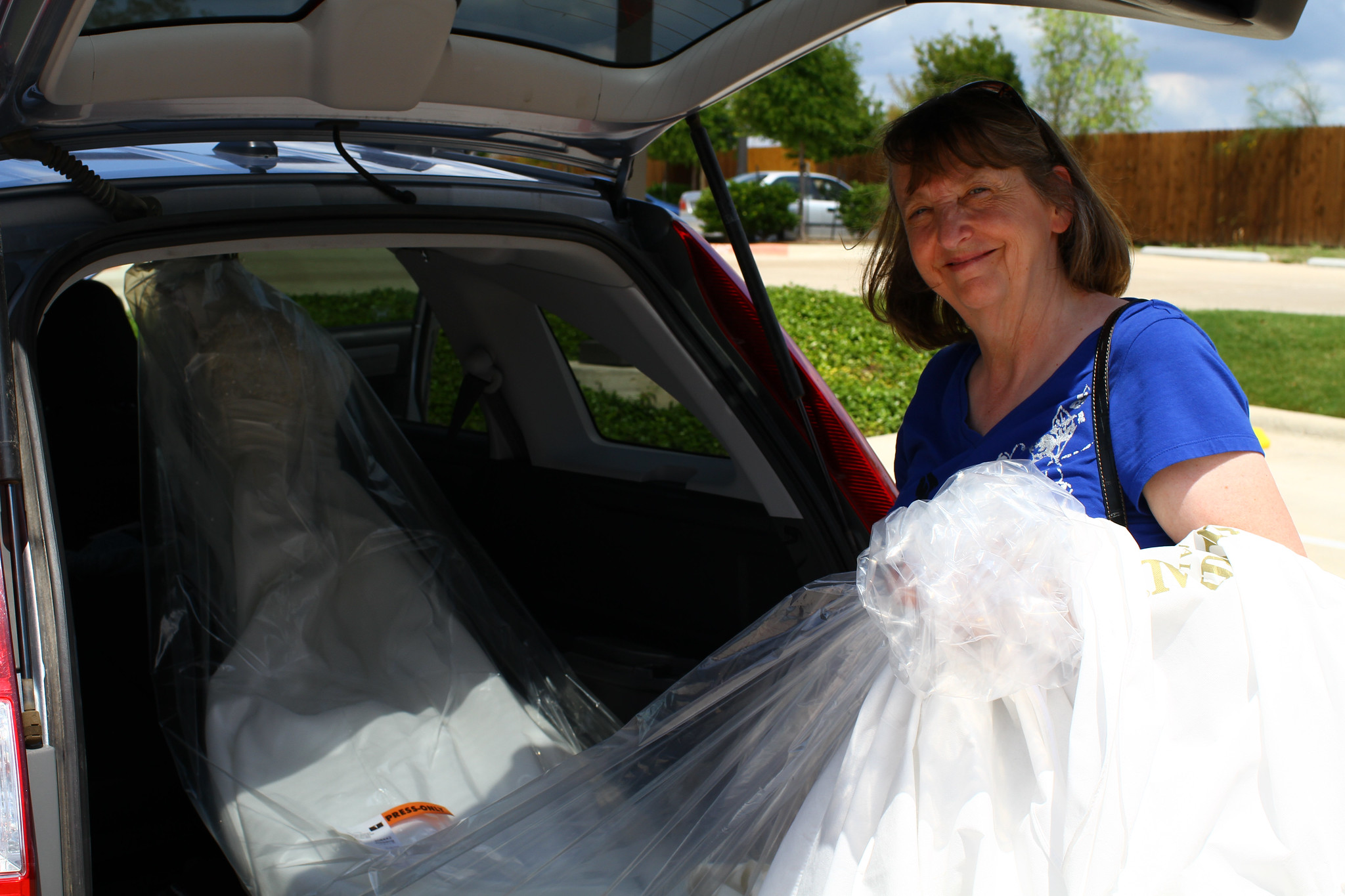 An elderly woman taking out a bridal dress from her car's trunk | Source: Flickr