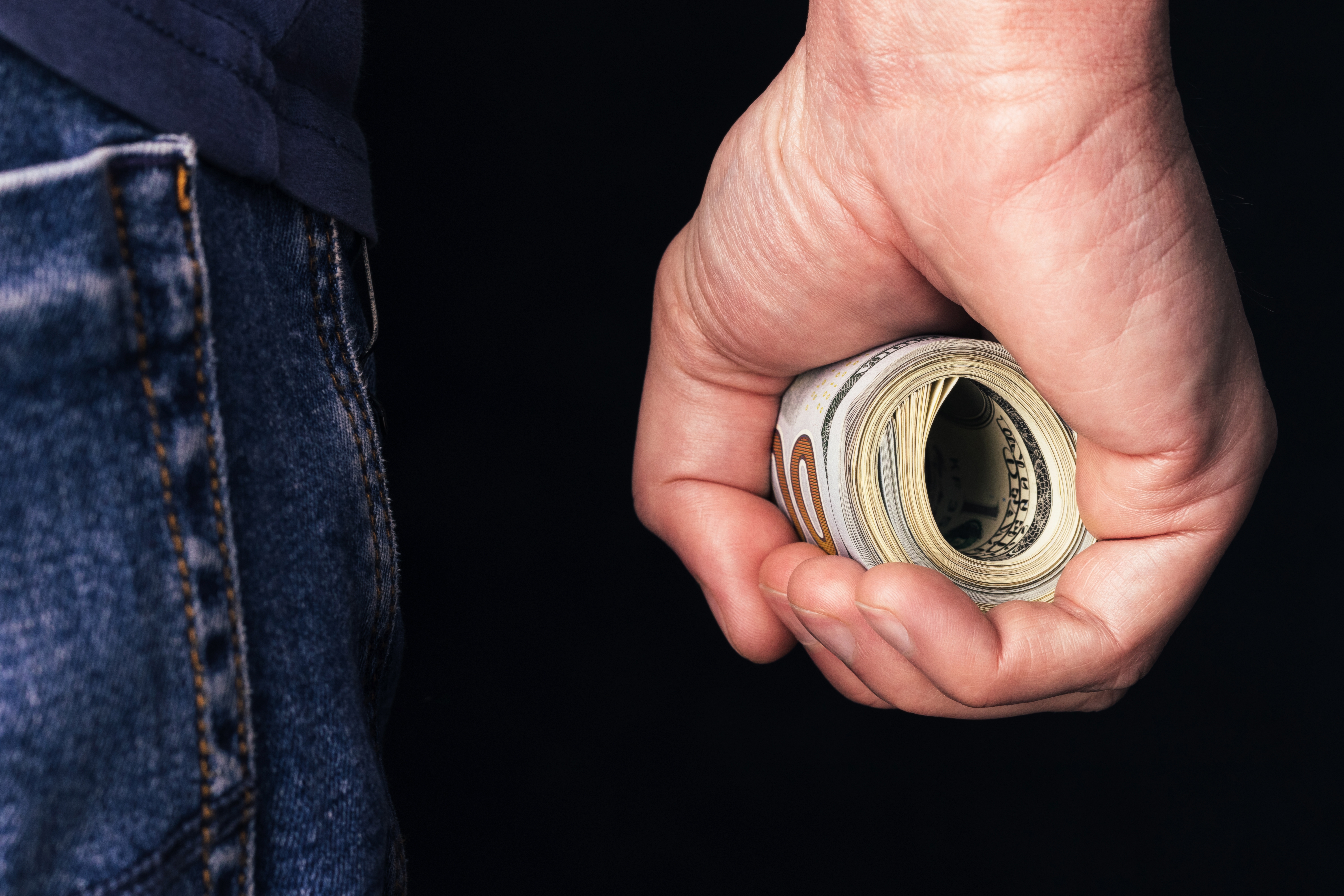 Roll of hundred us dollars in male fist. | Source: Shutterstock