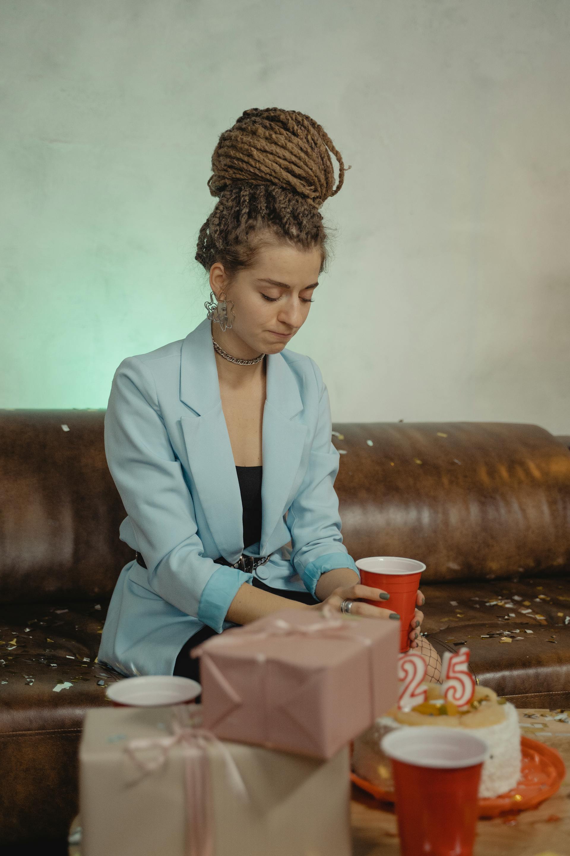 A woman sitting alone next to a birthday cake and presents | Source: Pexels