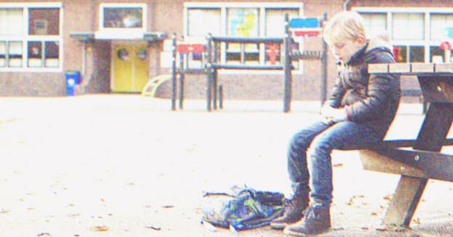 A kid sitting in a bench outside of school | Source: Shutterstock