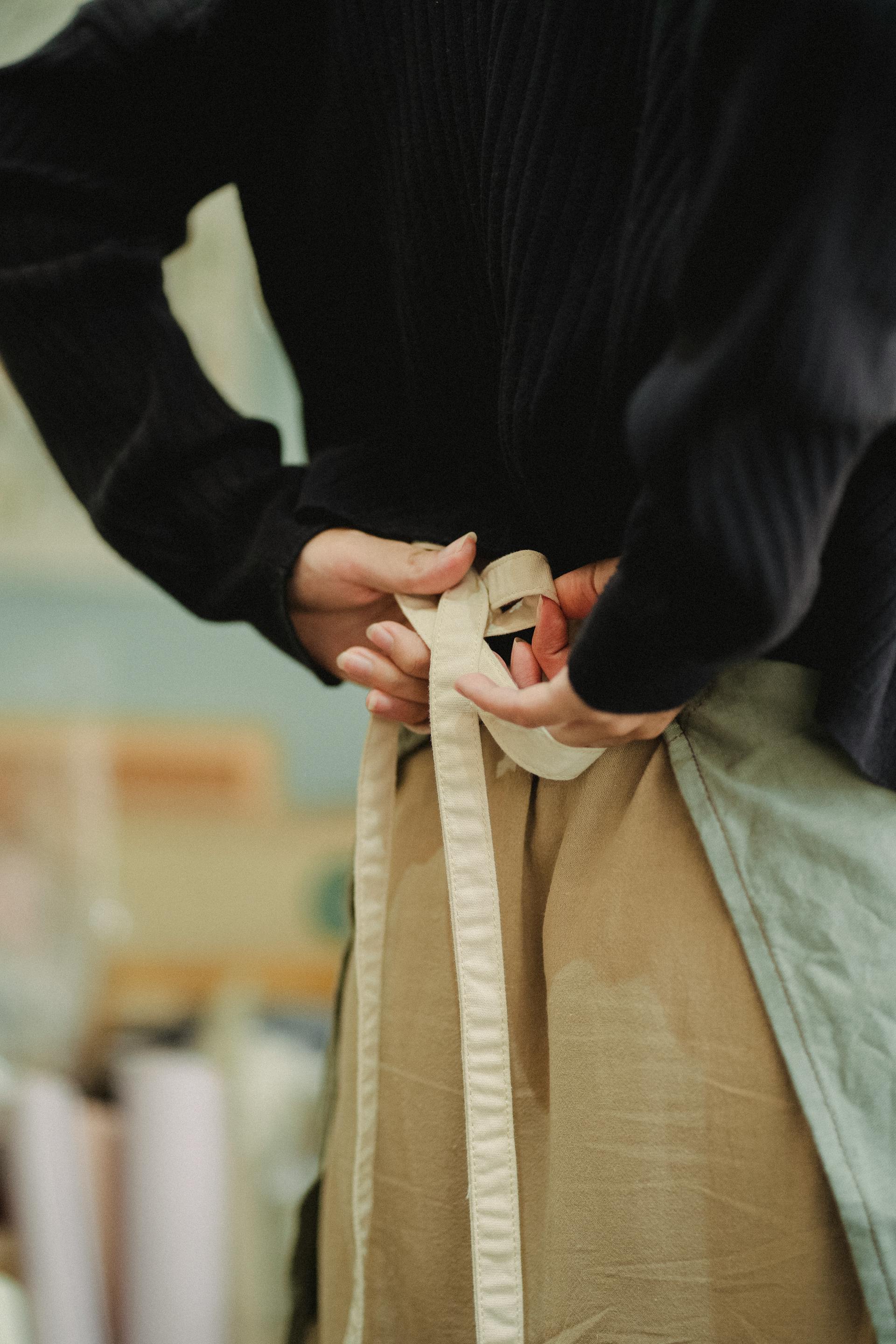 A person tying an apron | Source: Pexels
