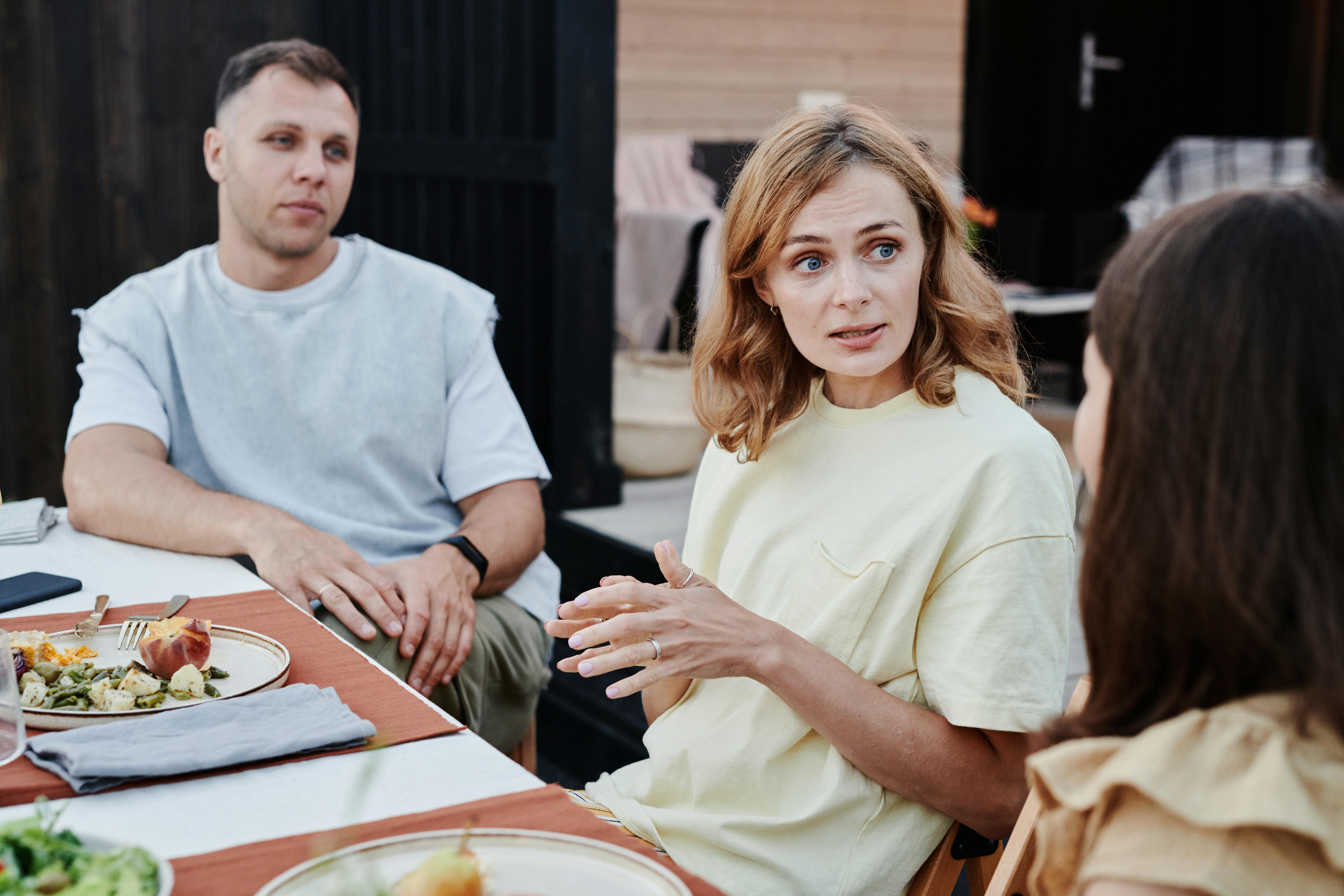 A man and two women talking at a table | Source: Pexels