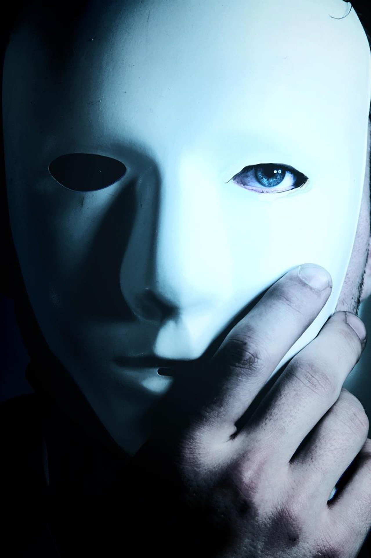 Pictured - A man with blue eyes wearing a mask with his hand holding it | Source: Pixabay 